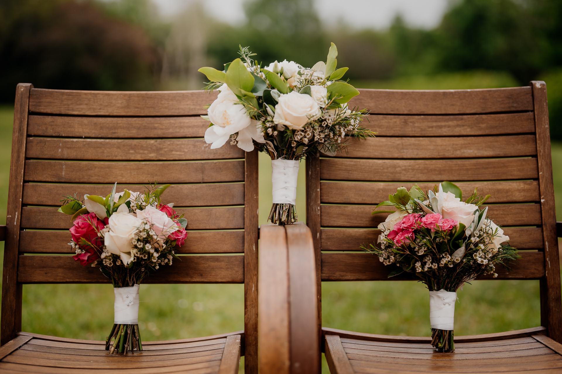 A couple of vases of flowers on a bench