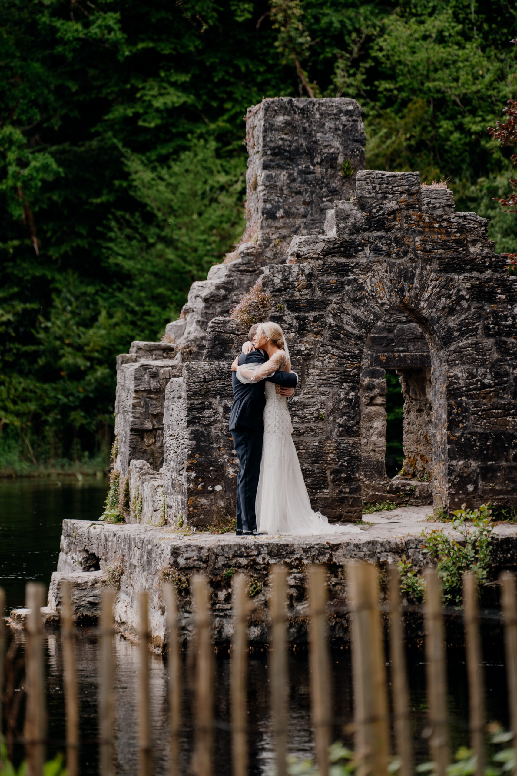 A man and woman kissing in front of a stone structure