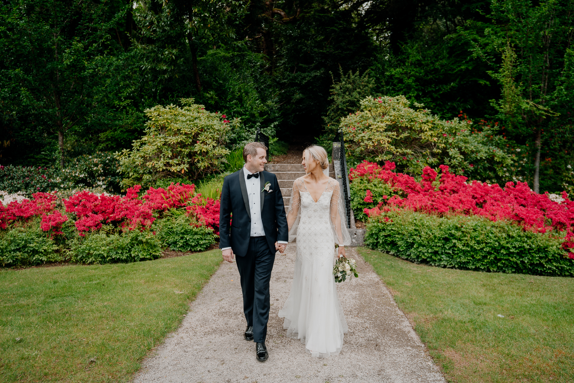 A man and woman walking down a path in a garden