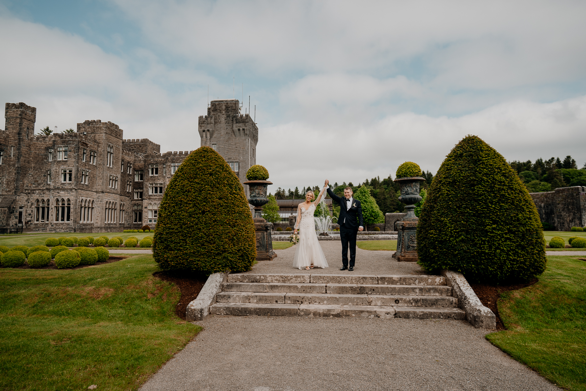 A bride and groom walking down a stone staircase in front of a castle