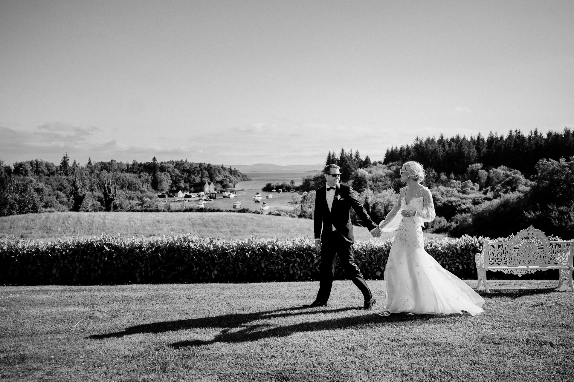 A man and woman walking down a path with a lake and trees