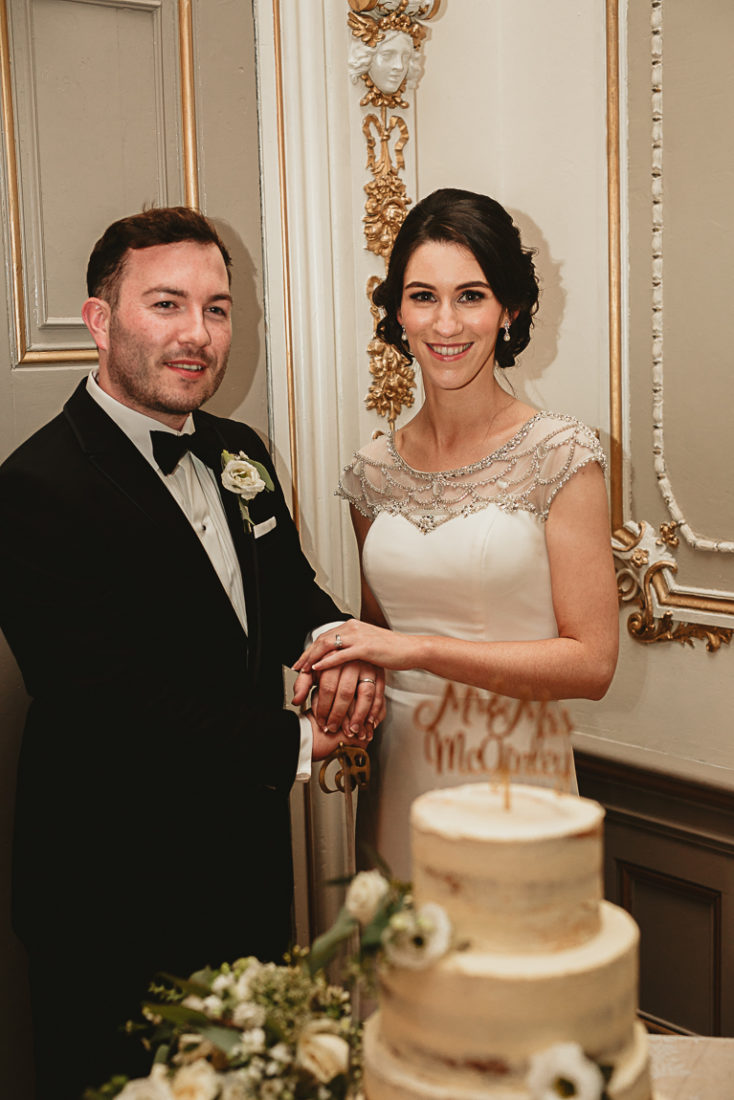 A man and a woman standing in front of a wedding cake