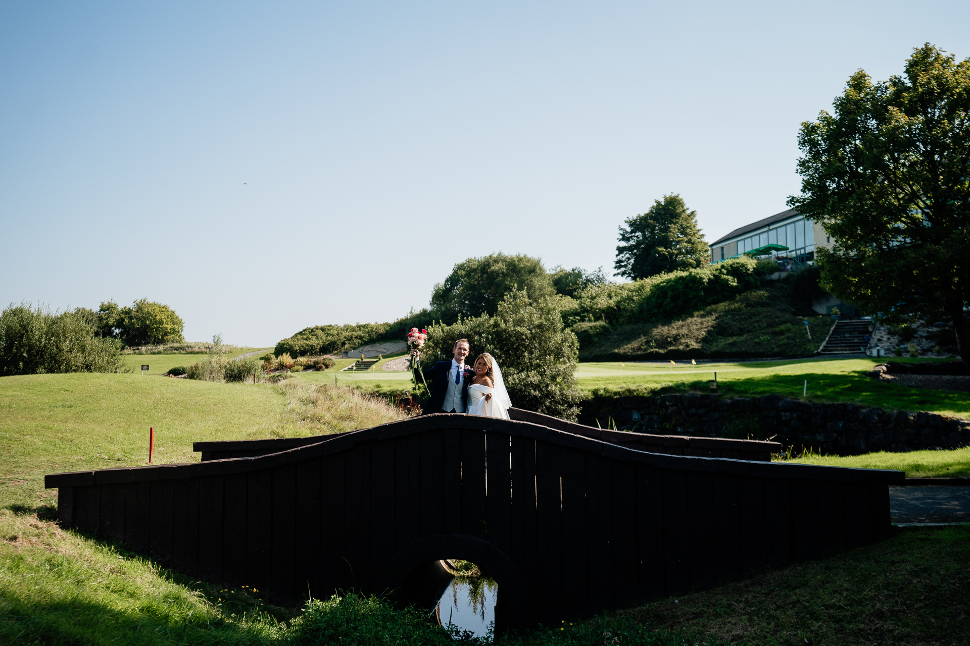 A man and woman posing on a stone bridge over a river