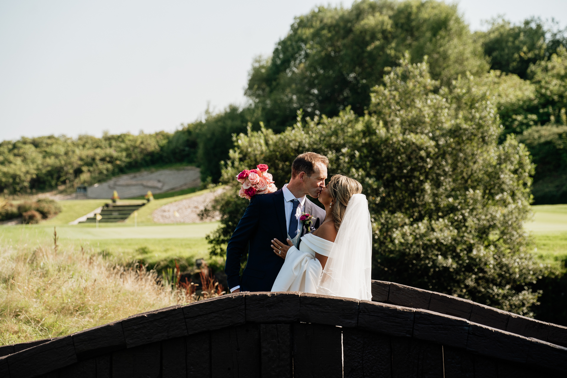 A man and woman kissing on a bridge