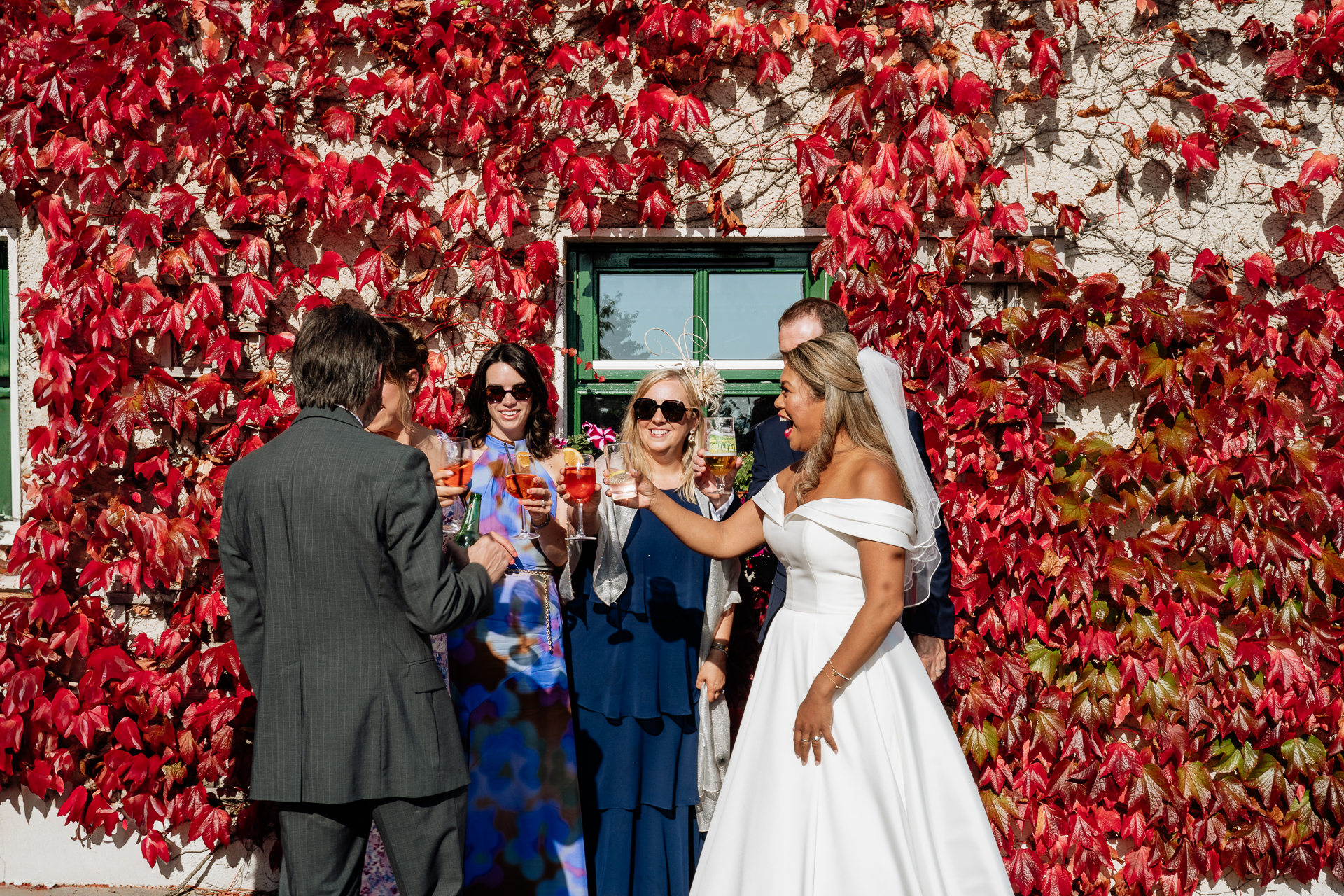 A group of people standing in front of a red wall with flowers