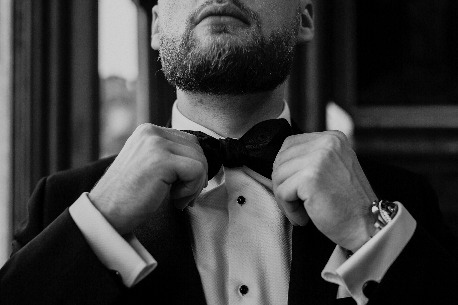 A man in a tuxedo tying his tie