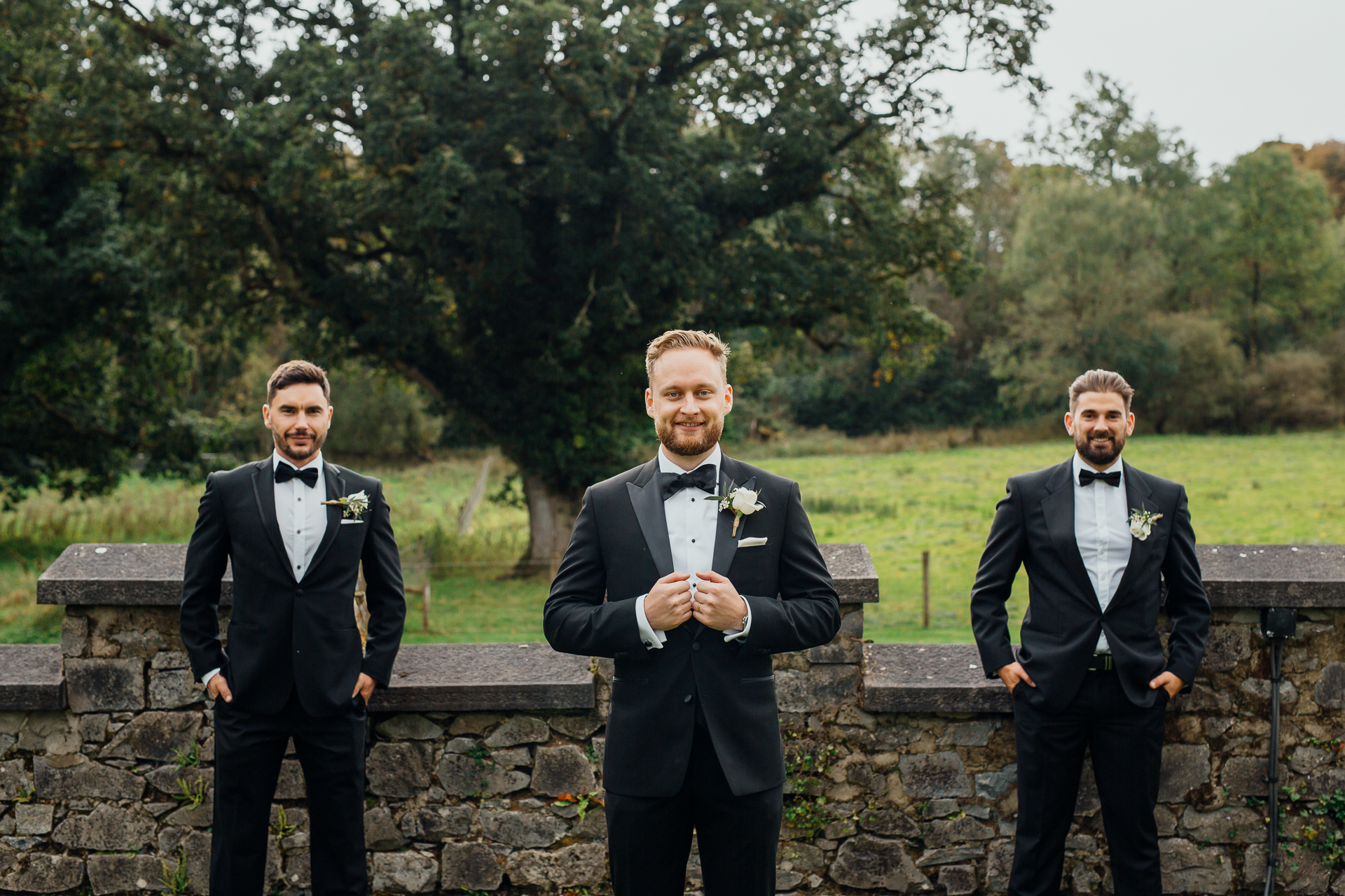 A group of men in tuxedos standing on a stone wall