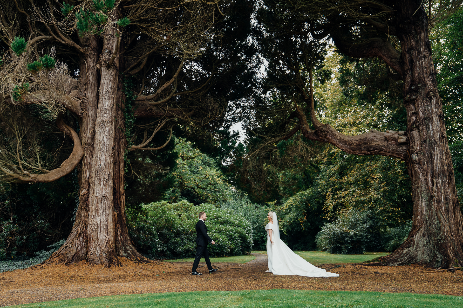 A man and woman walking down a path between trees