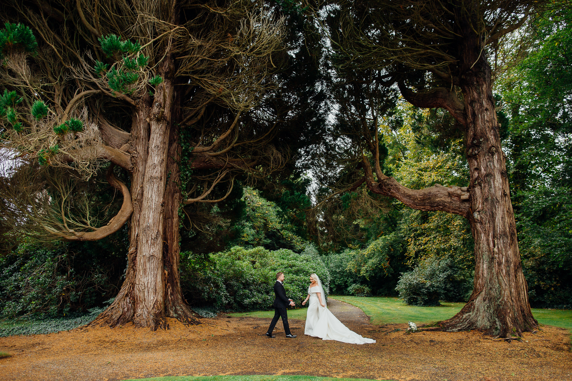 A man and woman walking down a path with trees on either side