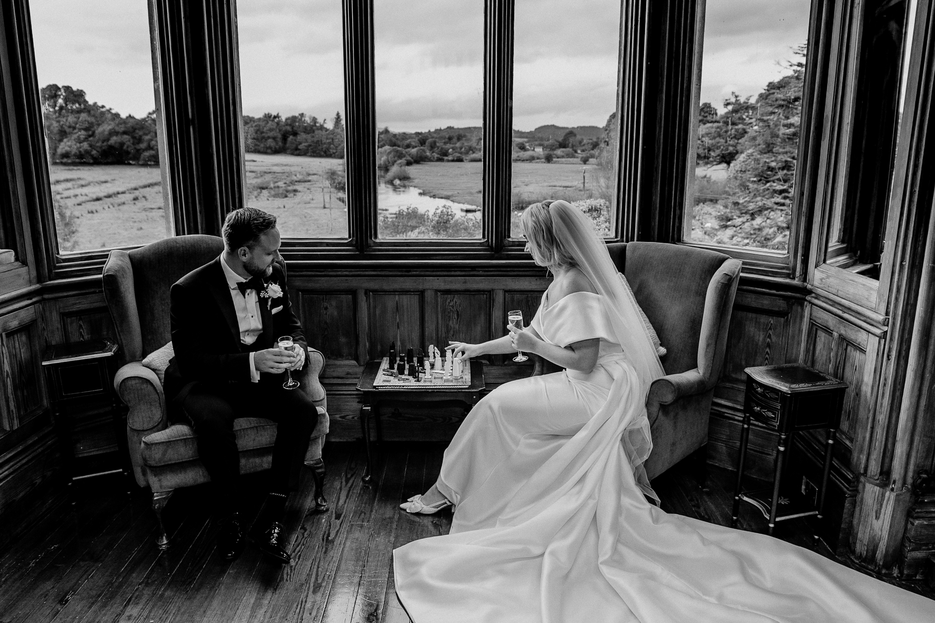 A bride and groom sitting at a table in a room with large windows