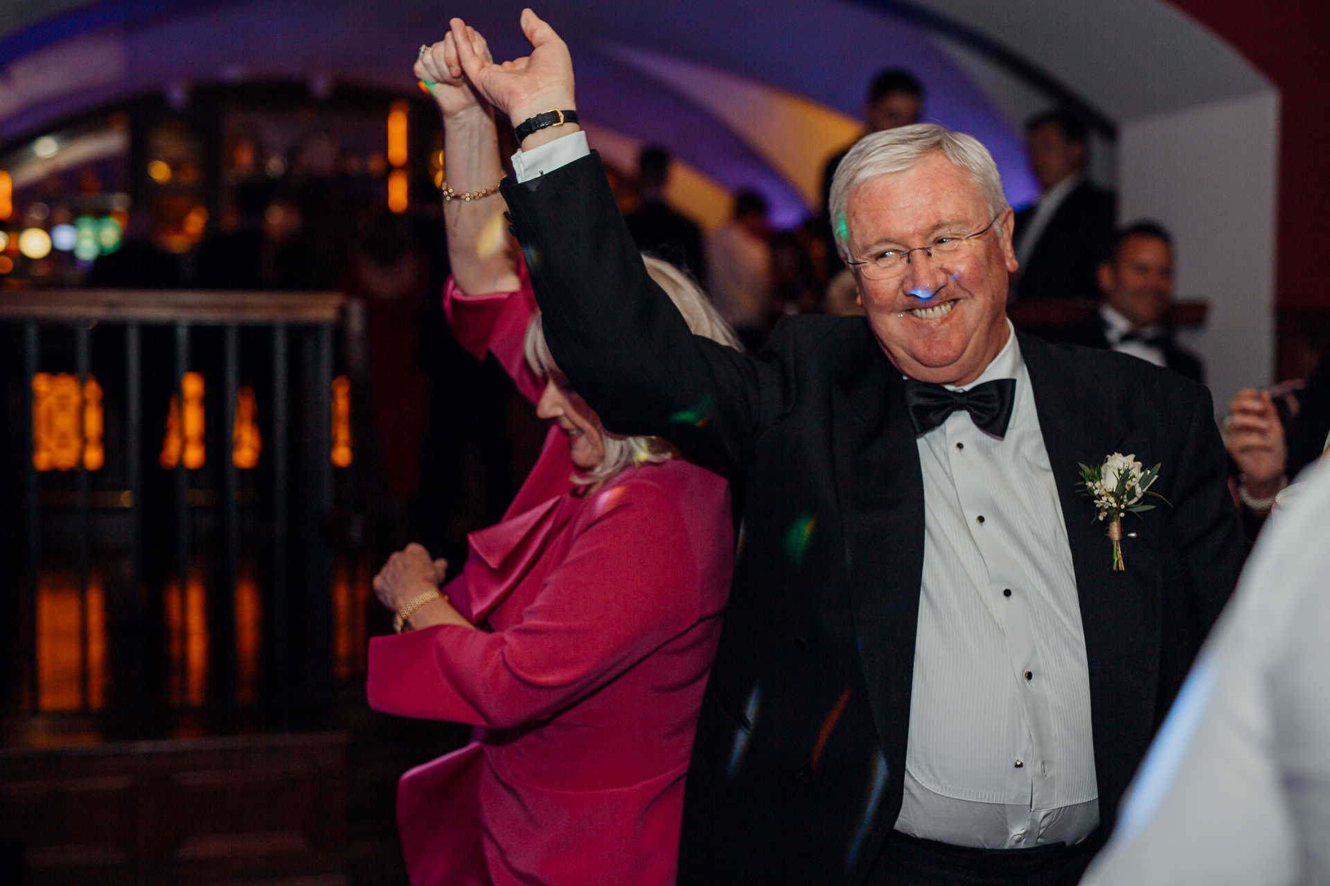 A man in a tuxedo with his hand up in the air