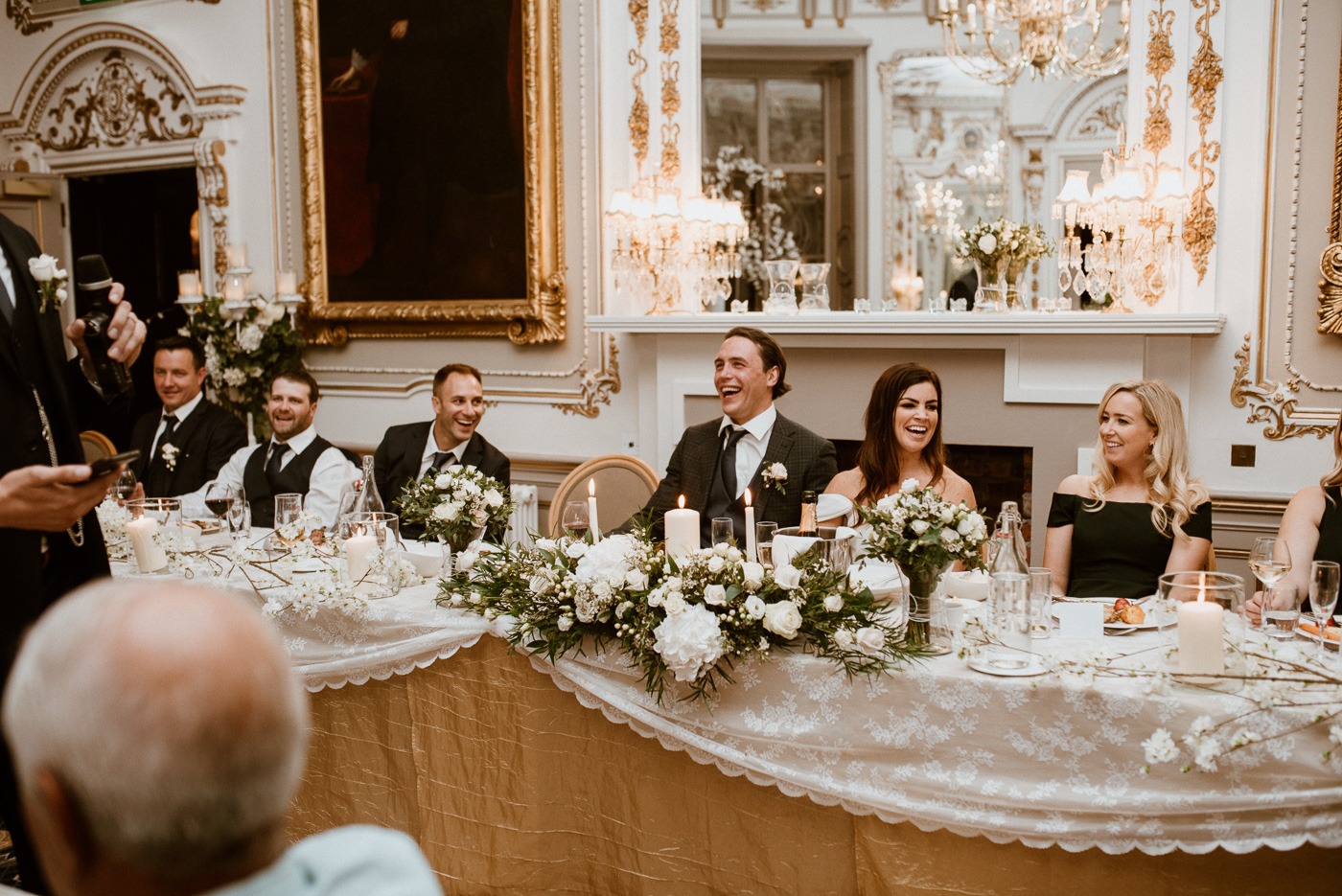 A group of people sitting at a table in front of a wedding cake