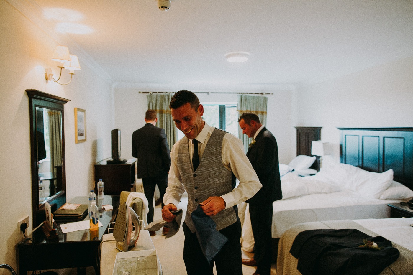 A man standing in a room with a bed and looking at the camera