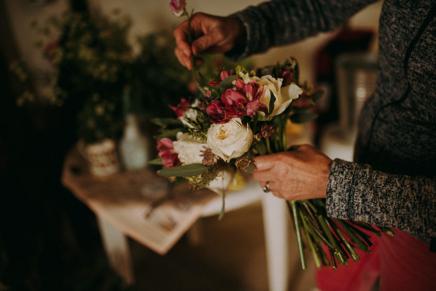 A person holding a vase of flowers on a table