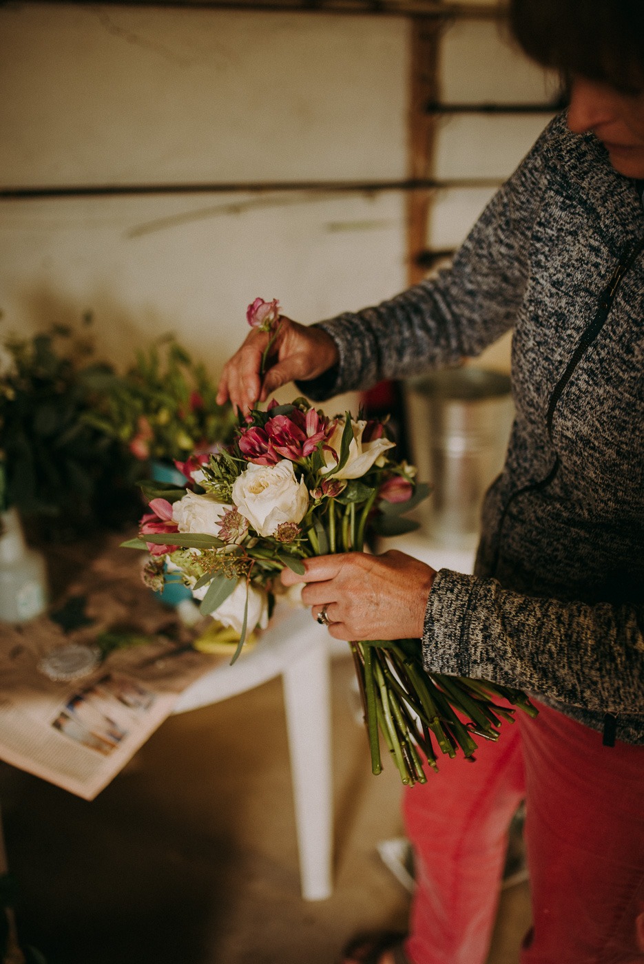 A person holding a vase of flowers on a table