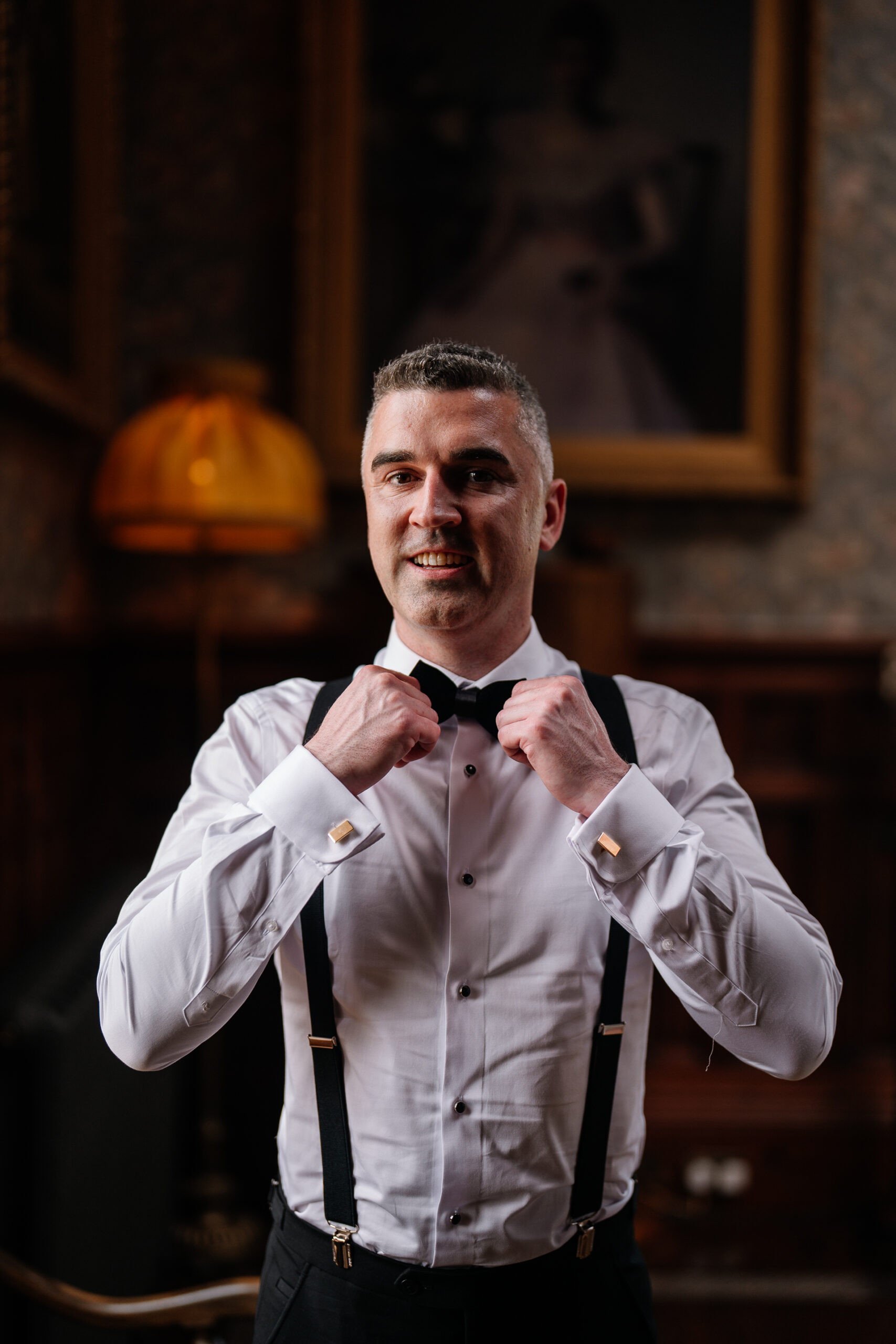 Groom adjusting his bow tie during wedding prep in Billiard Room at Markree Castle