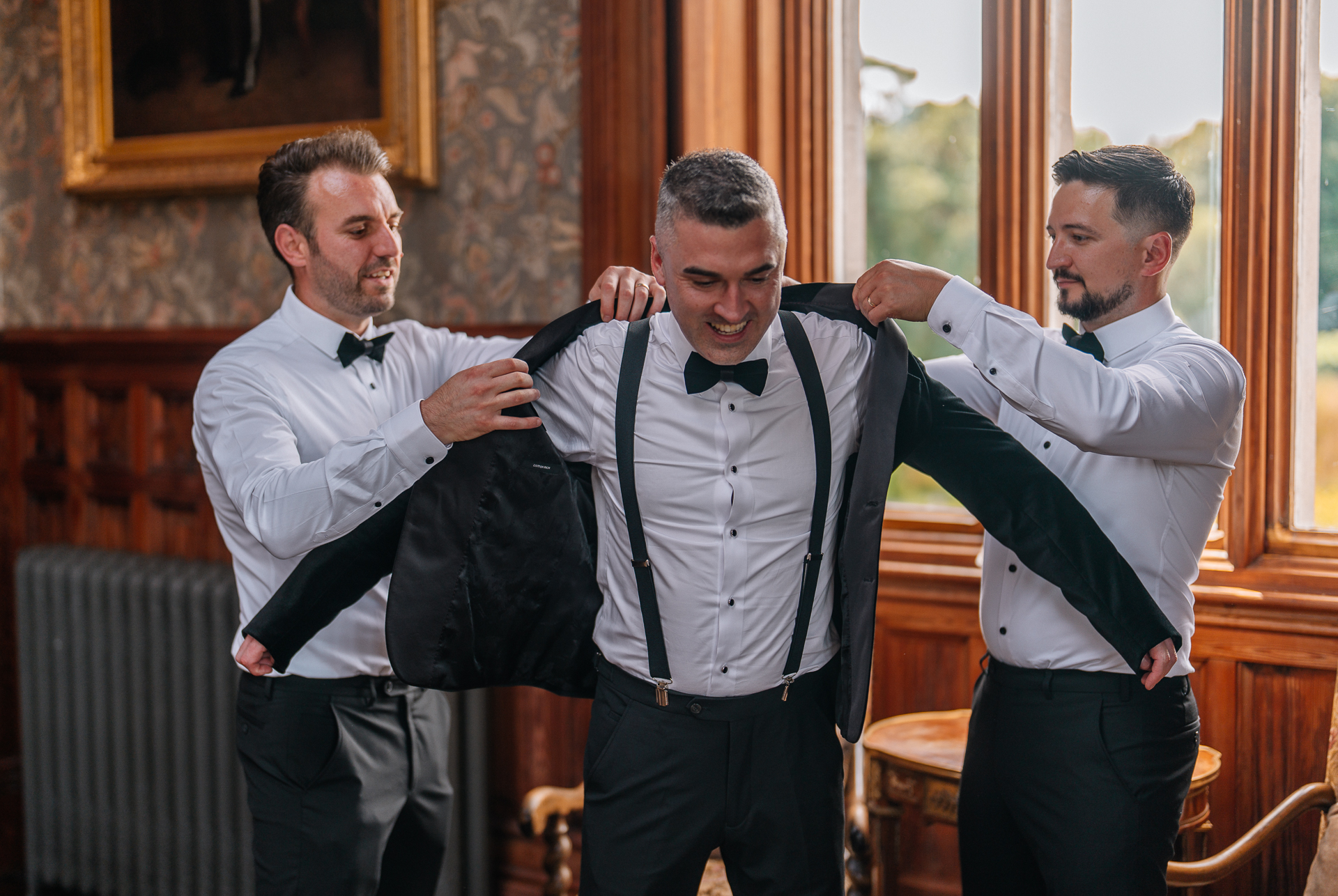 Groom adjusting his bow tie during wedding prep in Billiard Room at Markree Castle