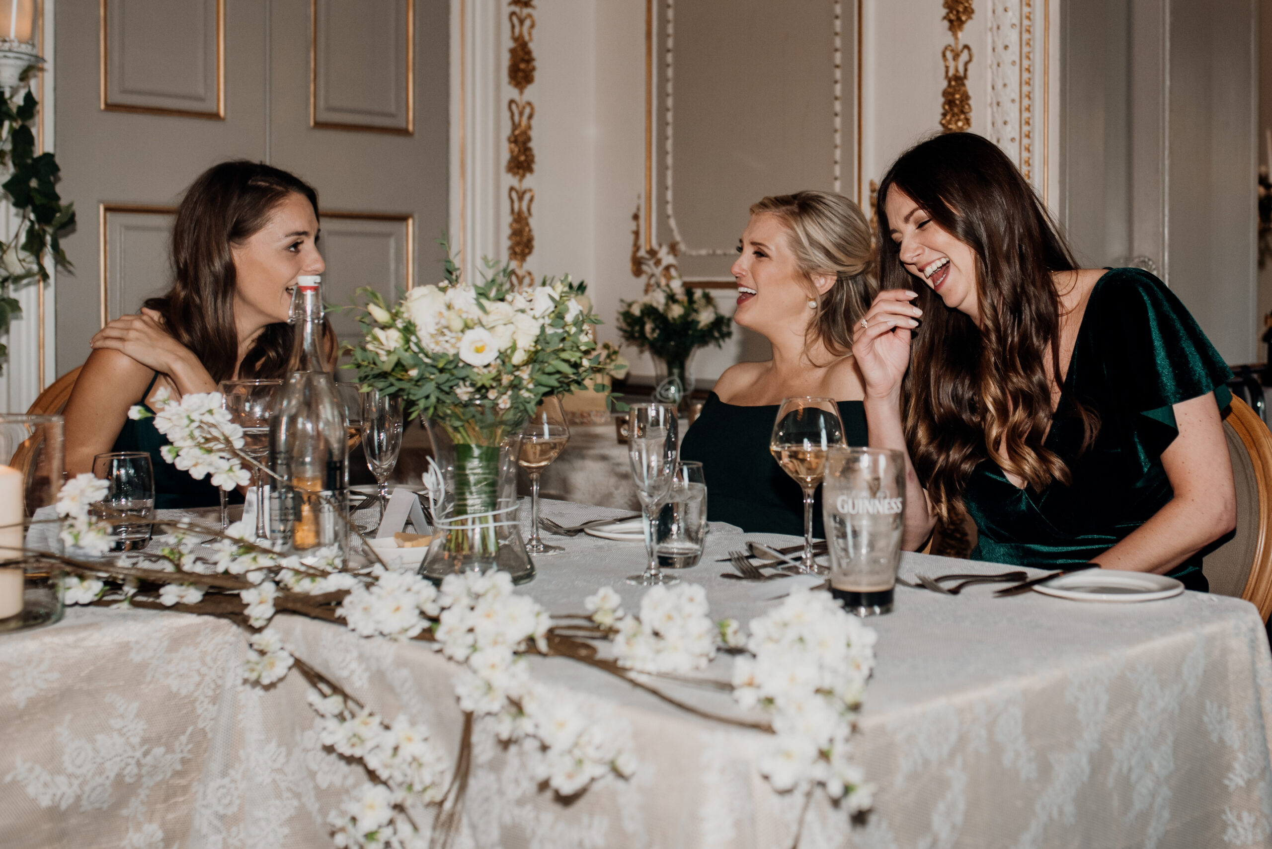 A group of women sitting at a table with flowers and glasses