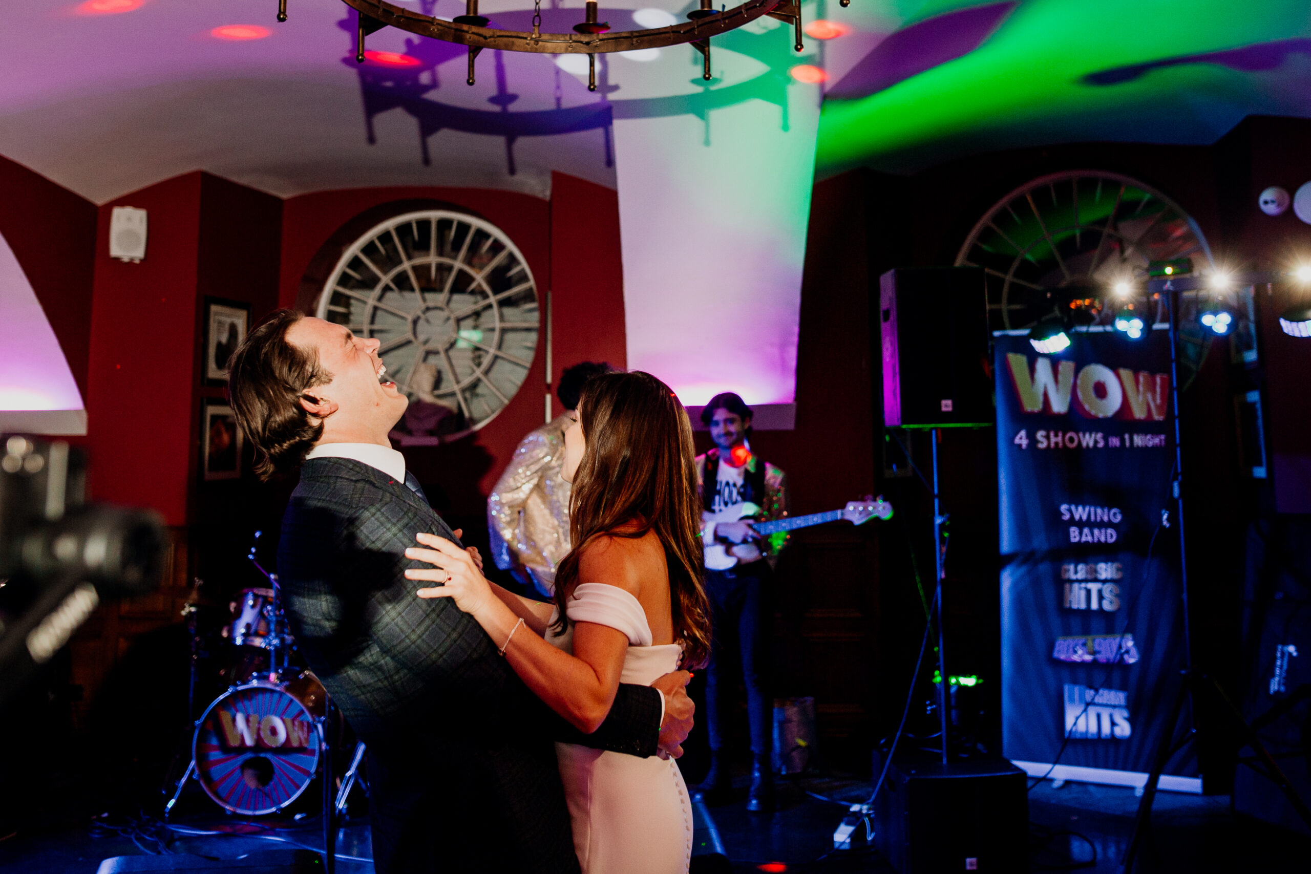 A man and woman kissing in front of a band playing instruments