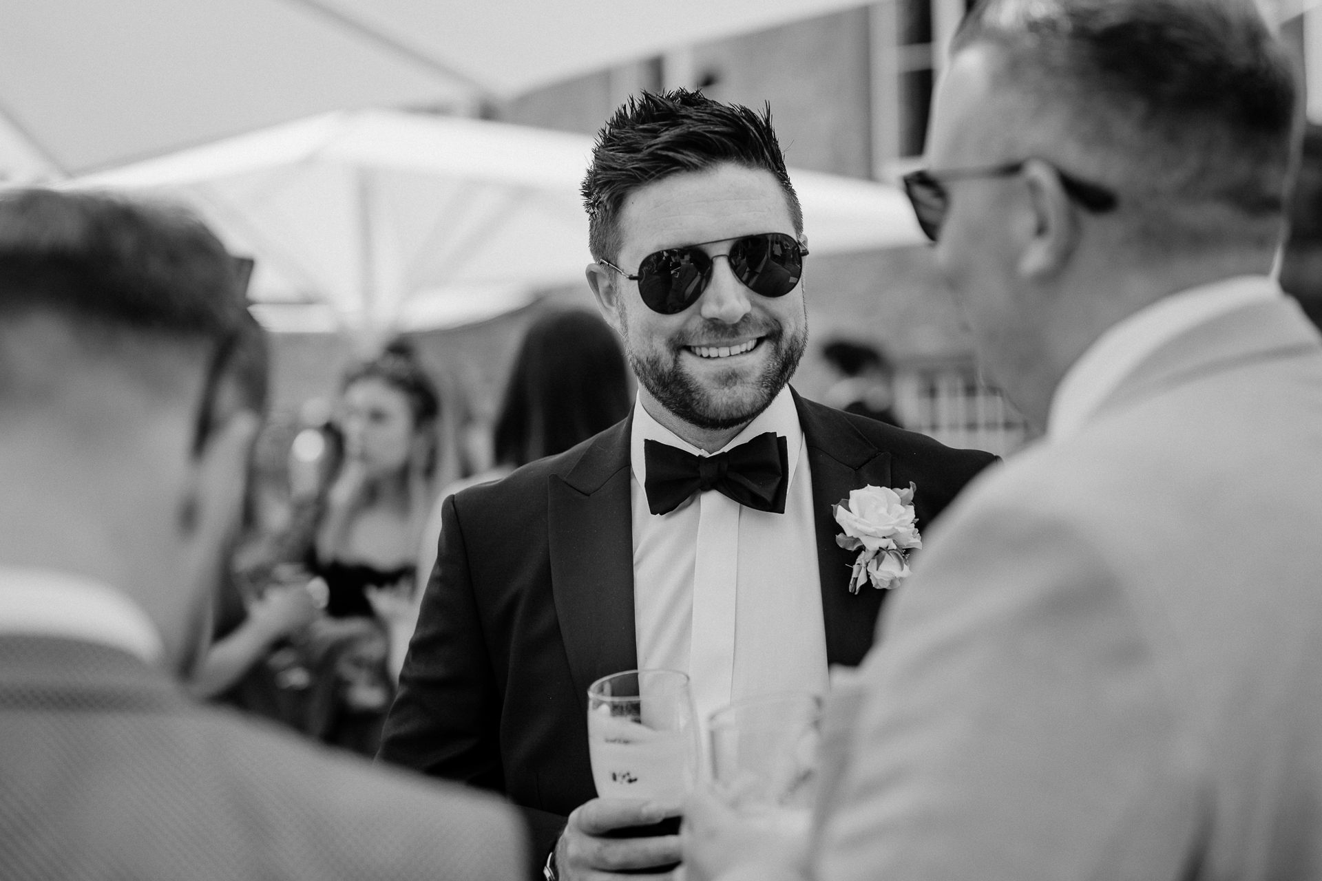 A man in a tuxedo holding a glass of wine