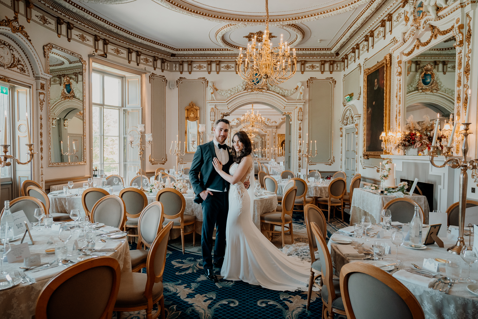 A man and woman kissing in a fancy room with tables and chairs