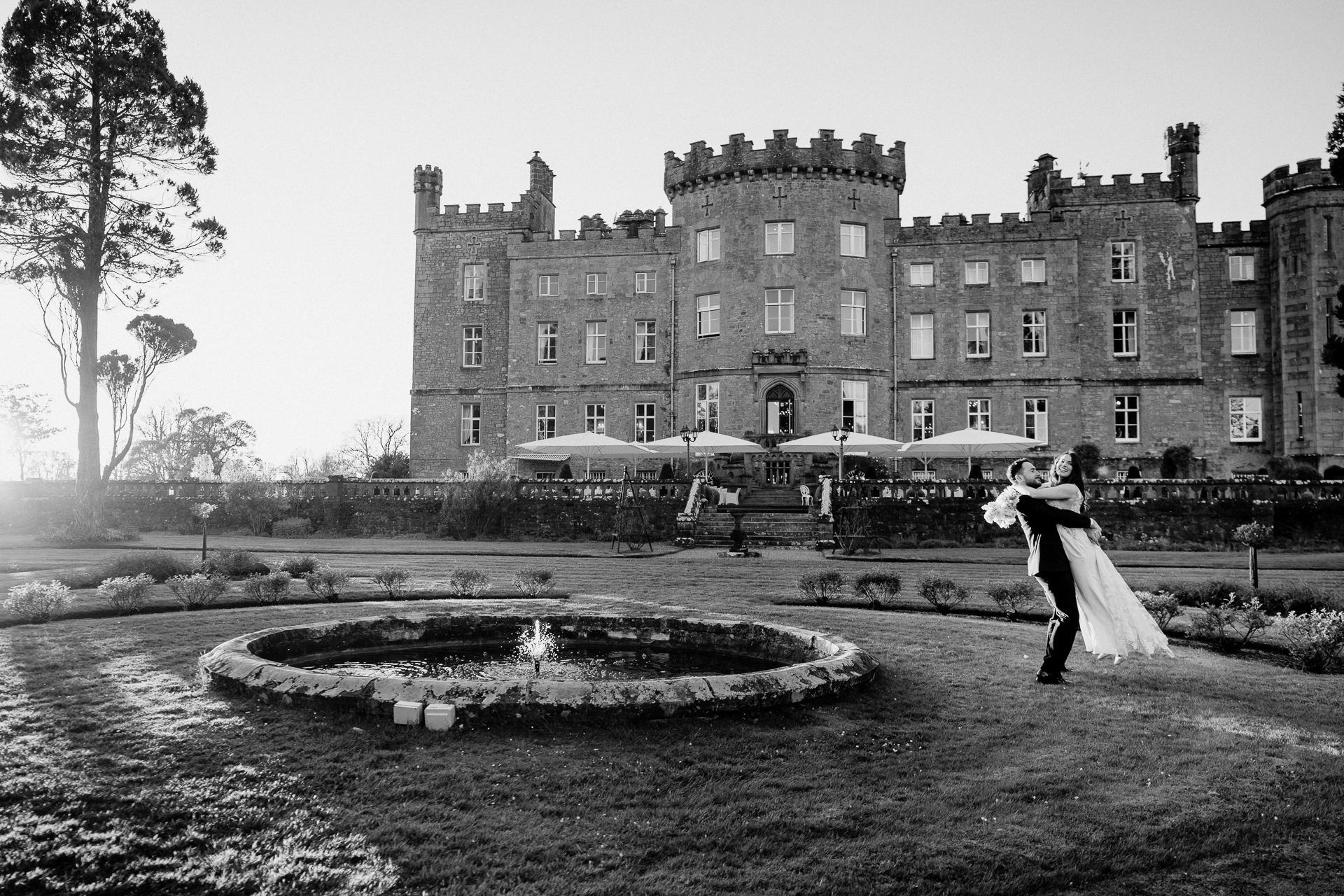 A man and woman kissing in front of a large building