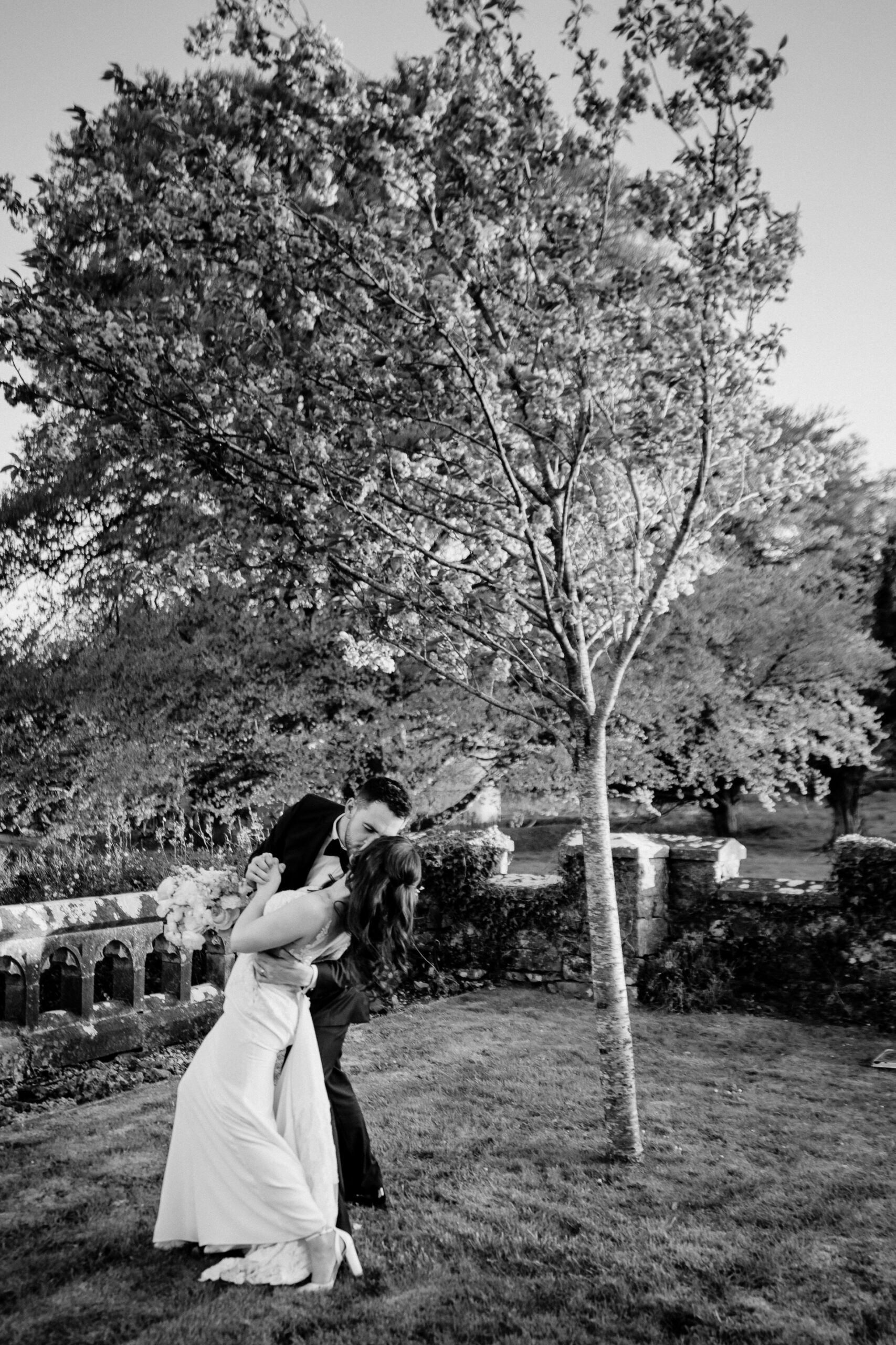 A man and woman kissing in front of a tree