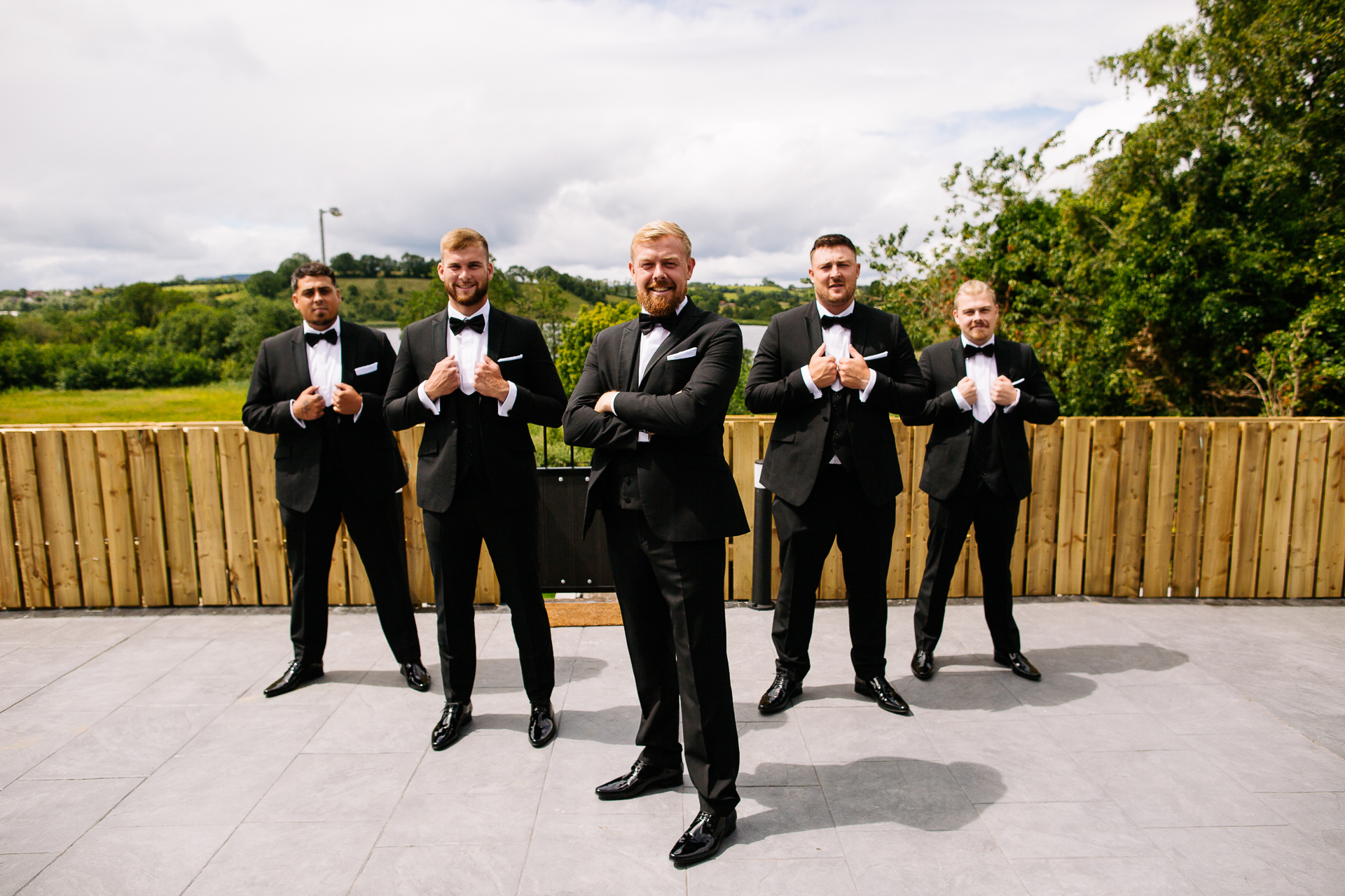 A group of men in tuxedos walking on a patio