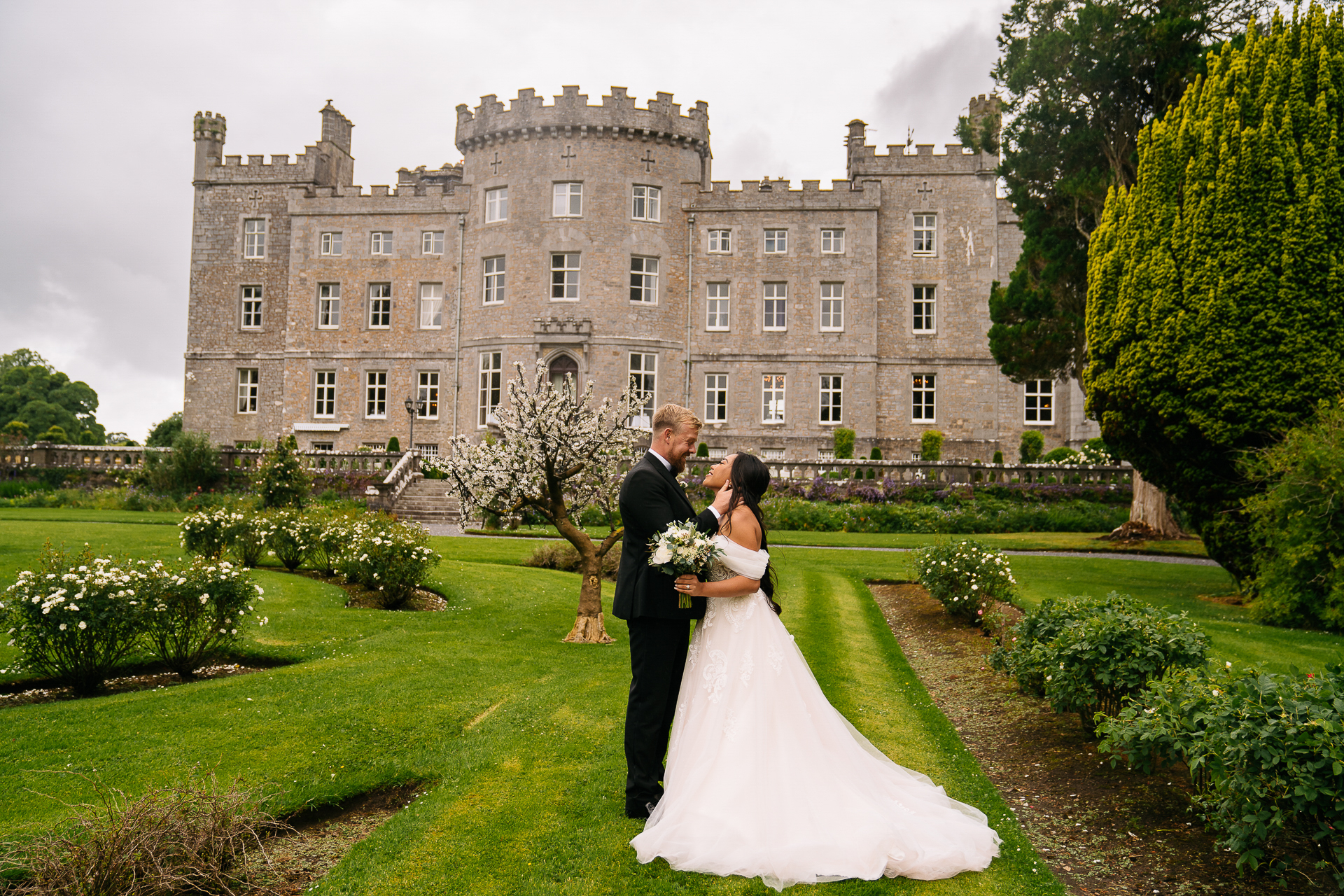 A man and woman in wedding attire kissing in front of a large building