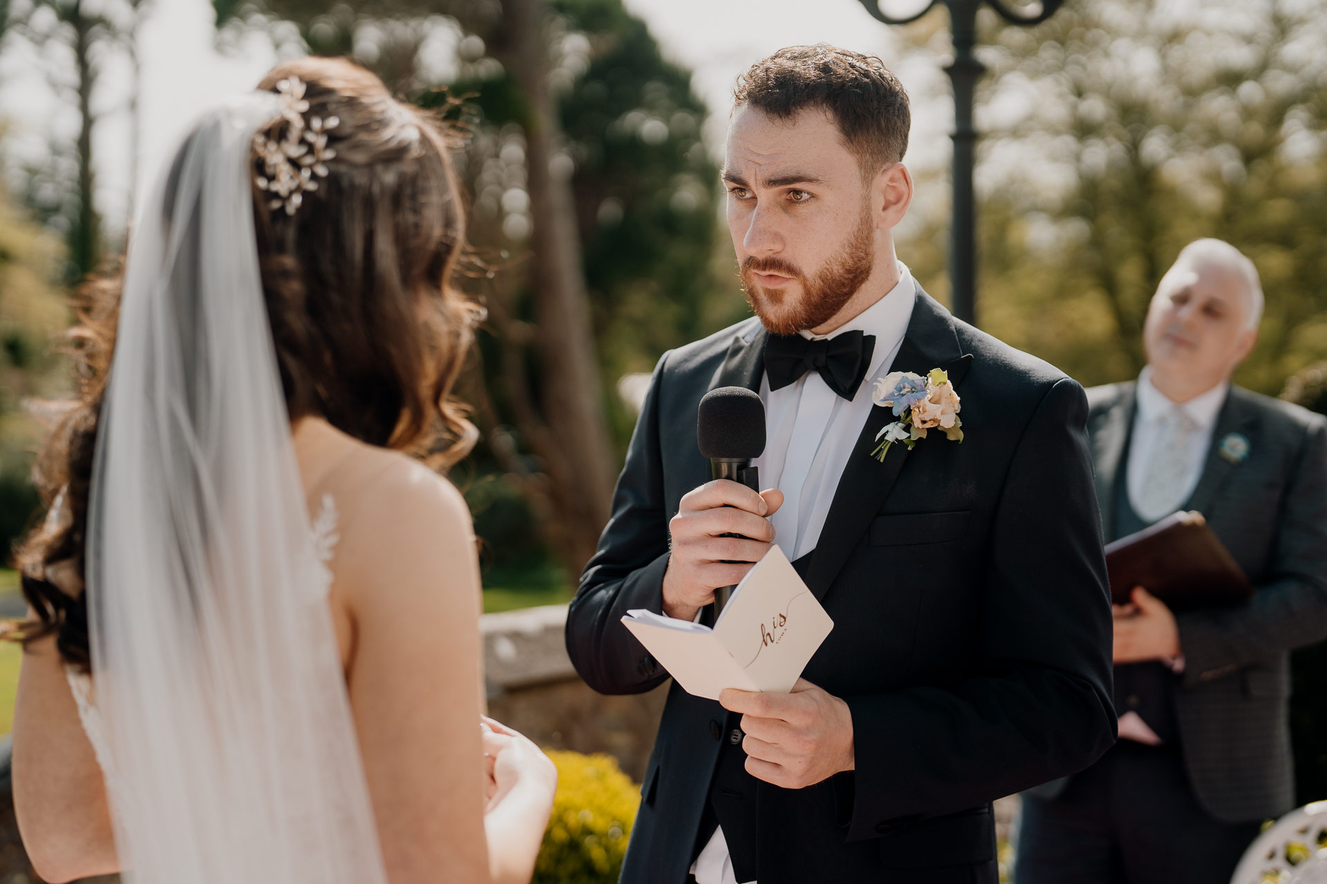 A man in a tuxedo holding a microphone and a woman in a dress