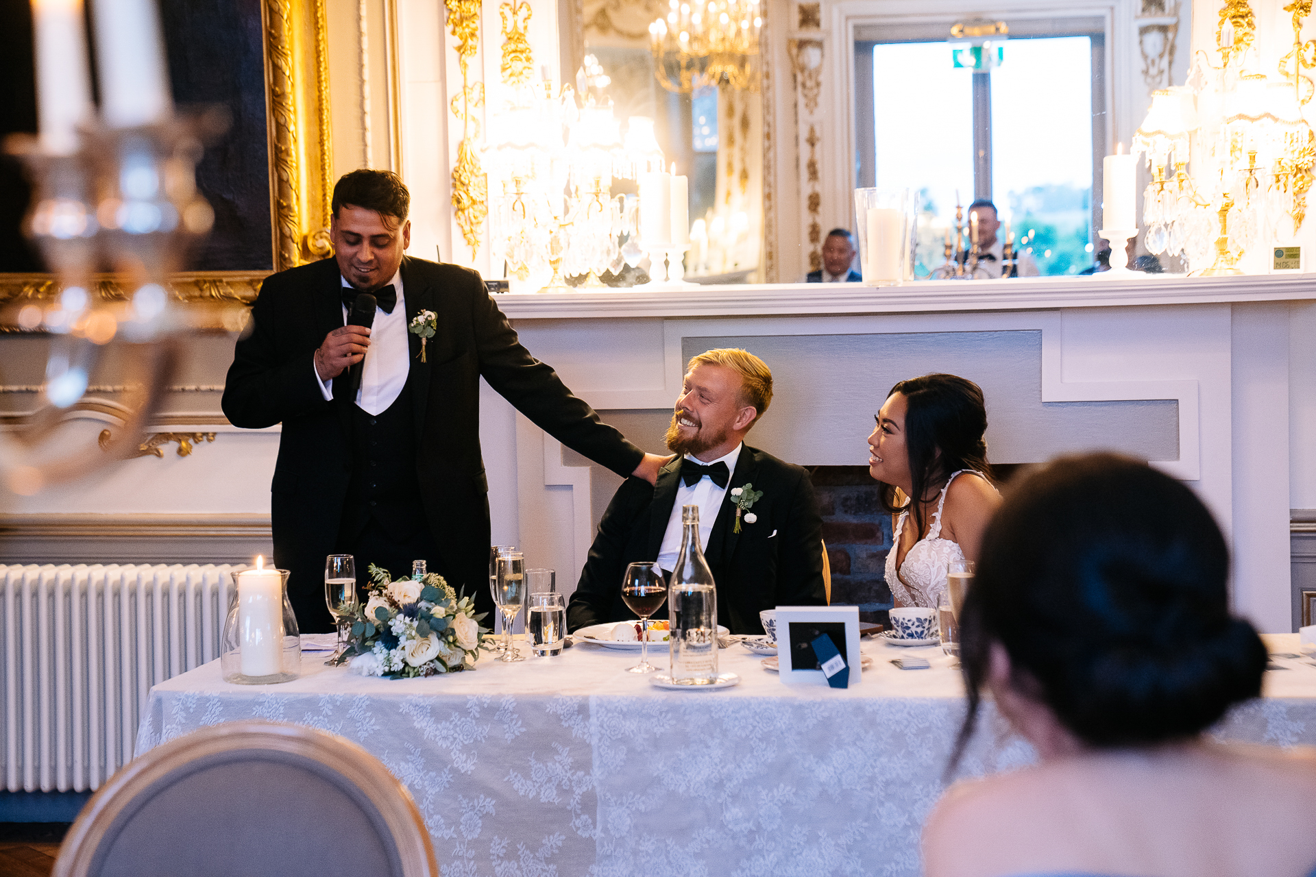 A man in a tuxedo standing at a table with a woman in a dress and a