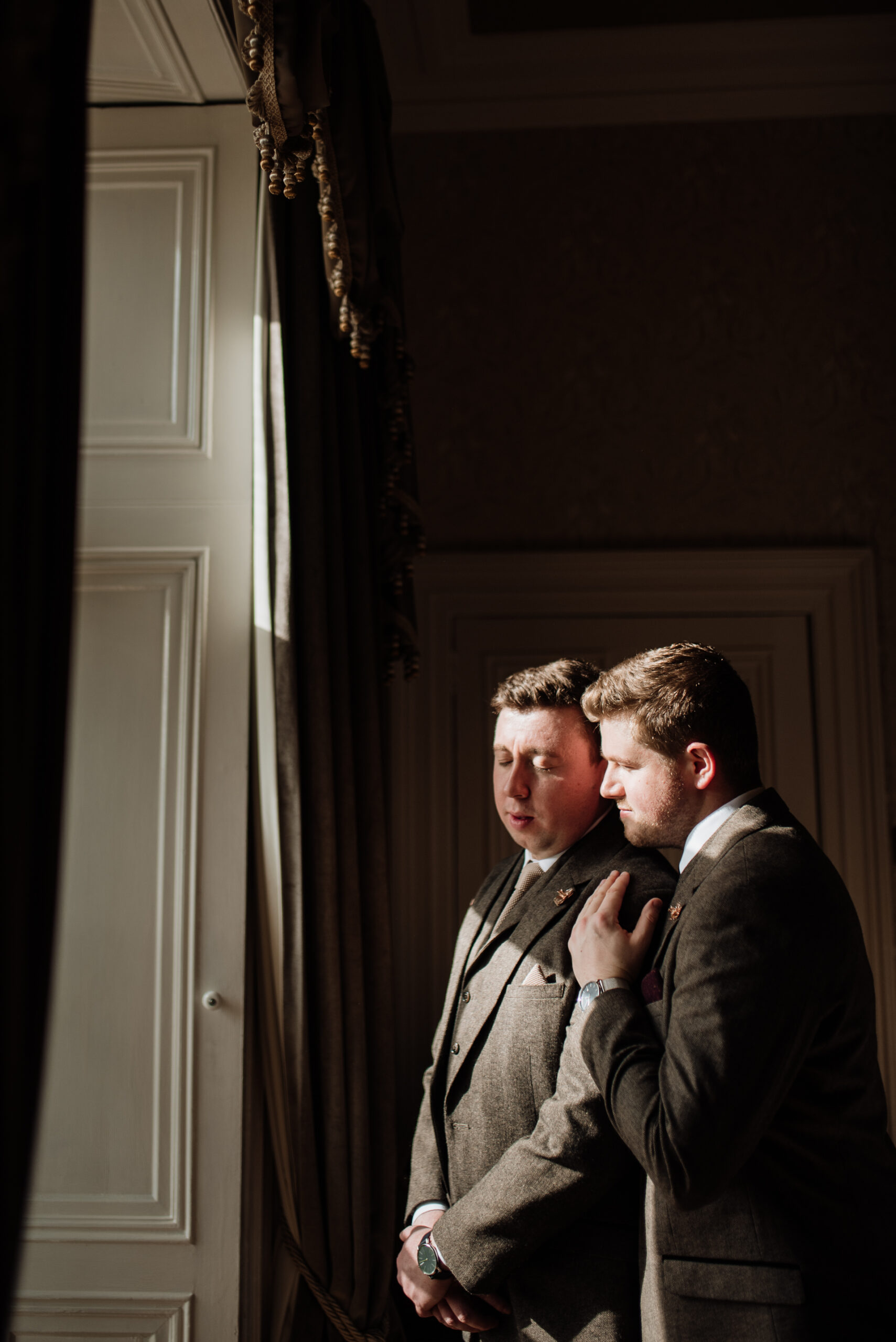 A man in a suit and a man in a suit looking at a door