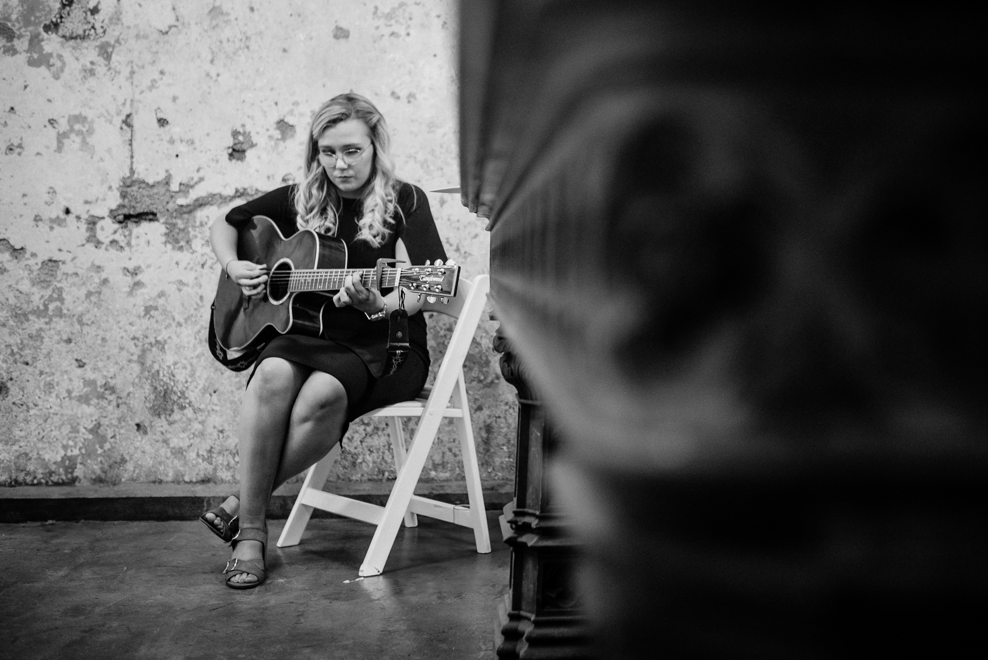 A woman sitting on a chair playing a guitar