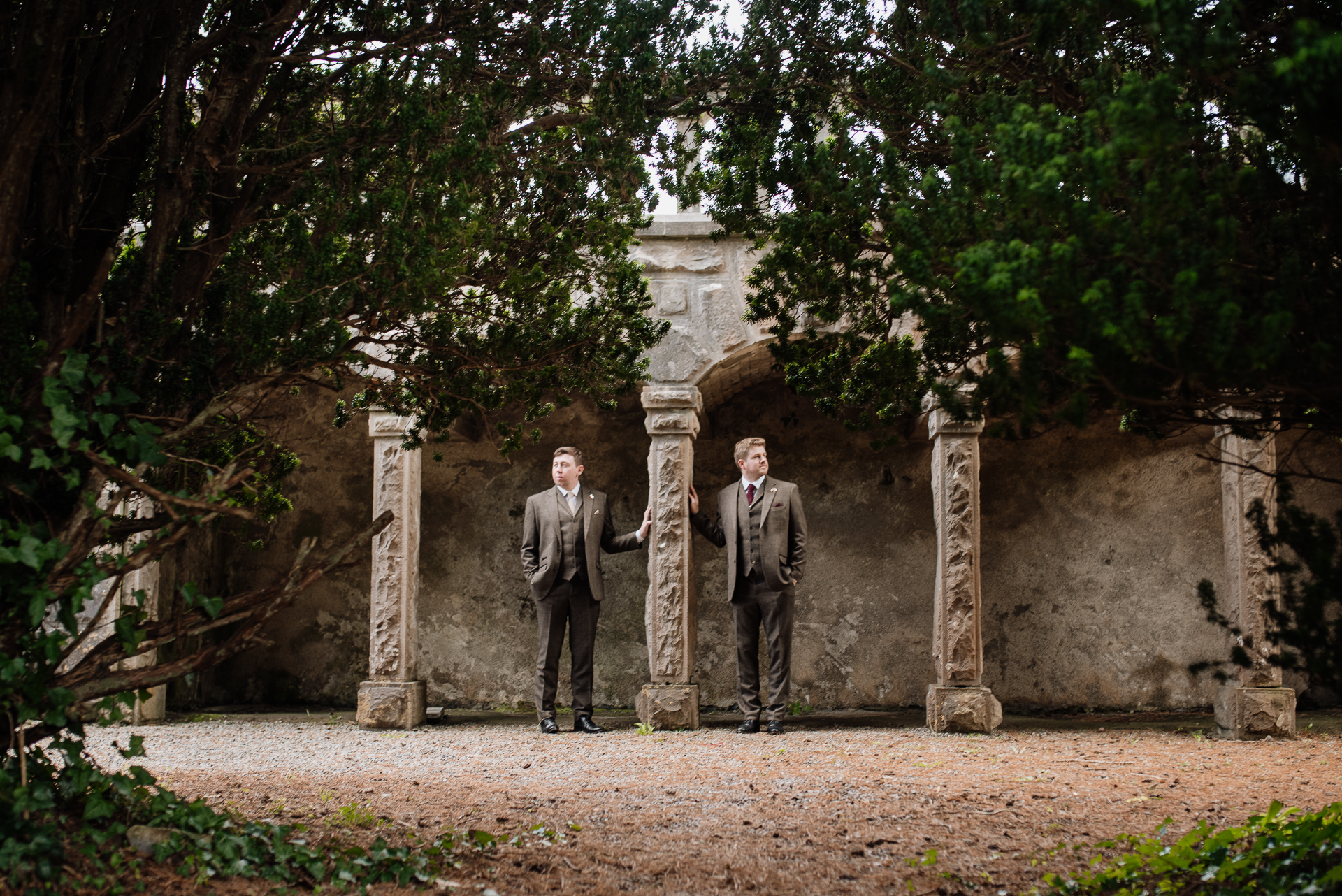 Two men standing in front of a stone wall with columns