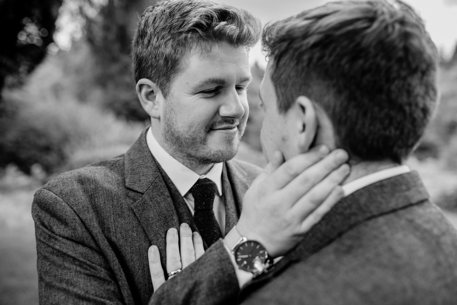 A man in a suit and tie kissing another man in a suit