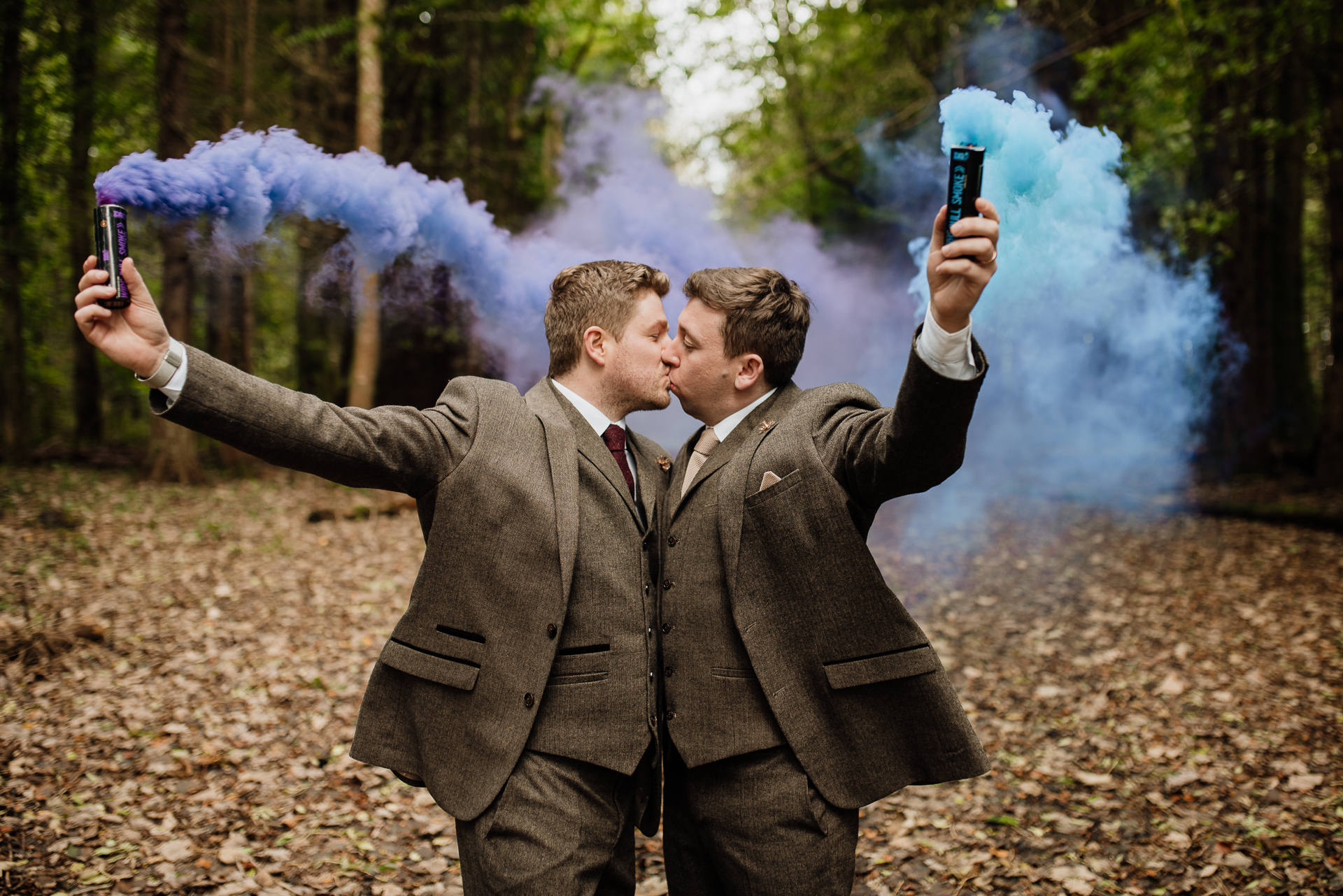 A couple of men in suits holding guns and looking at a large blue smoke cloud