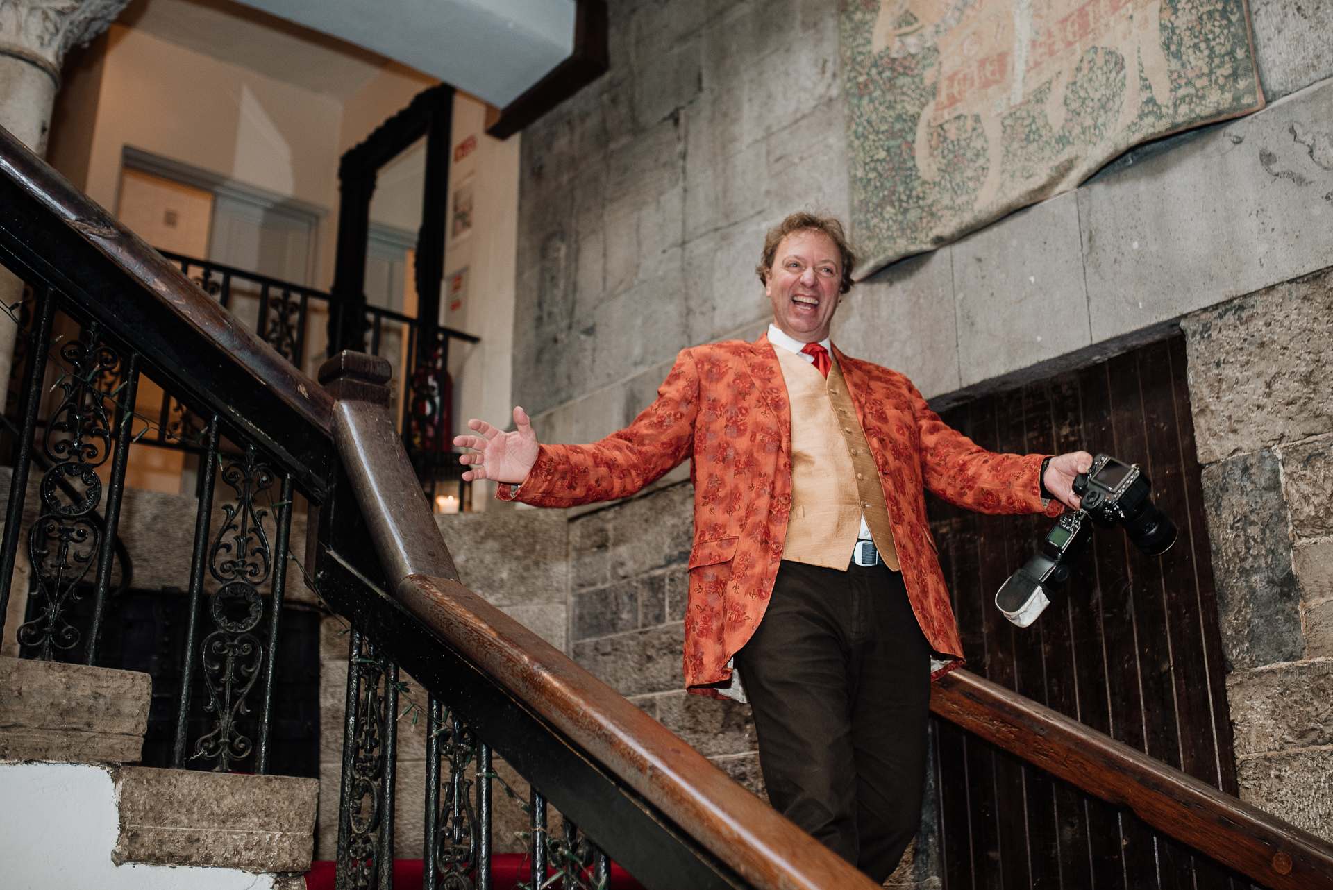 A person in a suit holding a gun on a staircase