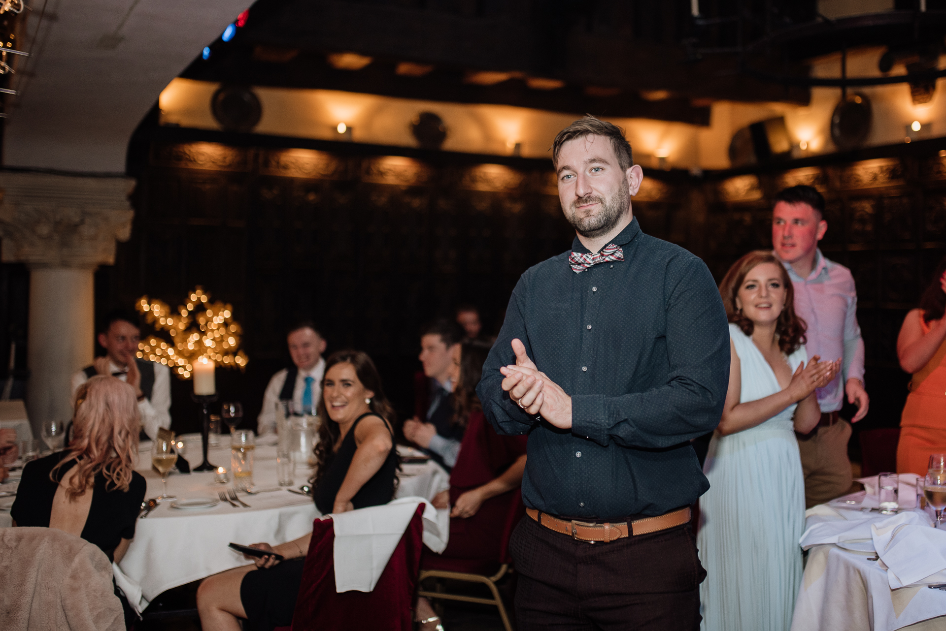 A person standing in a room with people sitting at tables and chairs