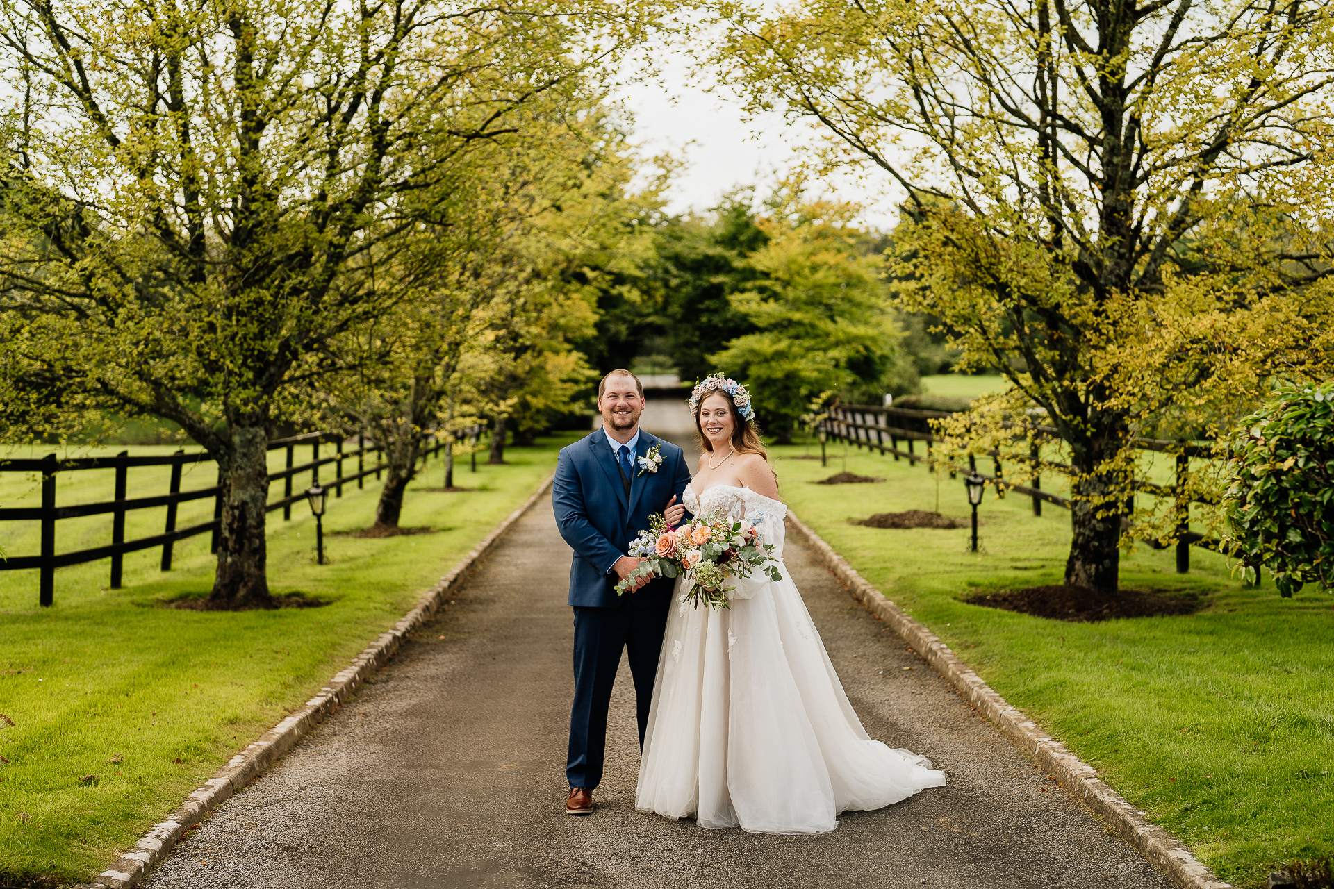 A man and woman in wedding attire walking down a path in a park