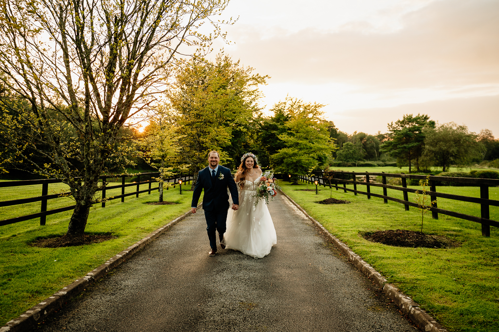 A man and woman walking down a path with grass and trees on either side of them