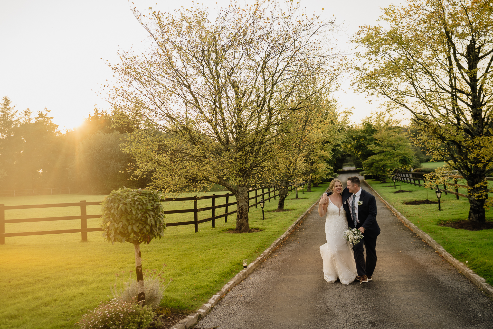 A man and woman kissing on a road with trees and grass