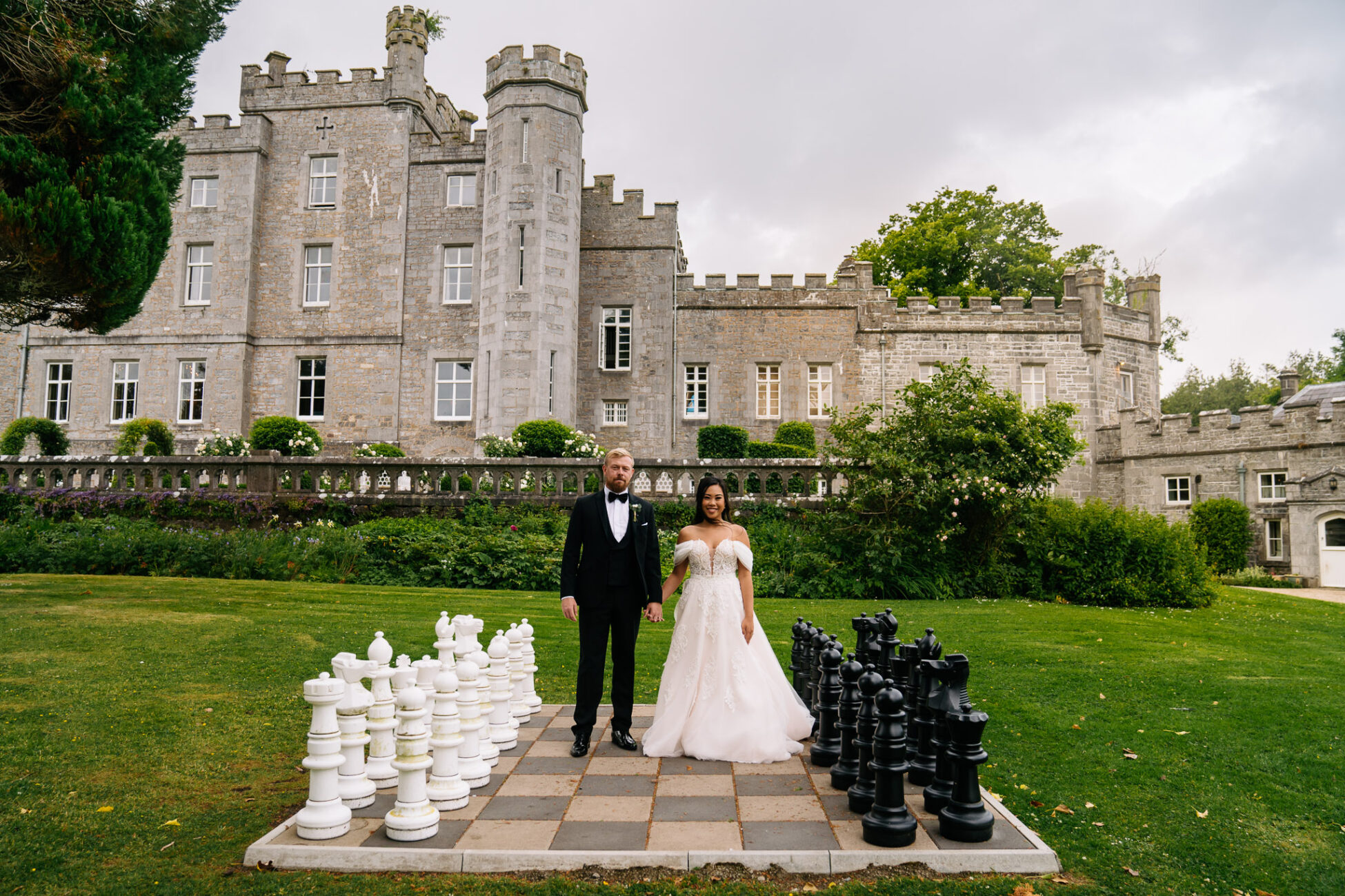 A man and woman in wedding attire standing in front of a castle