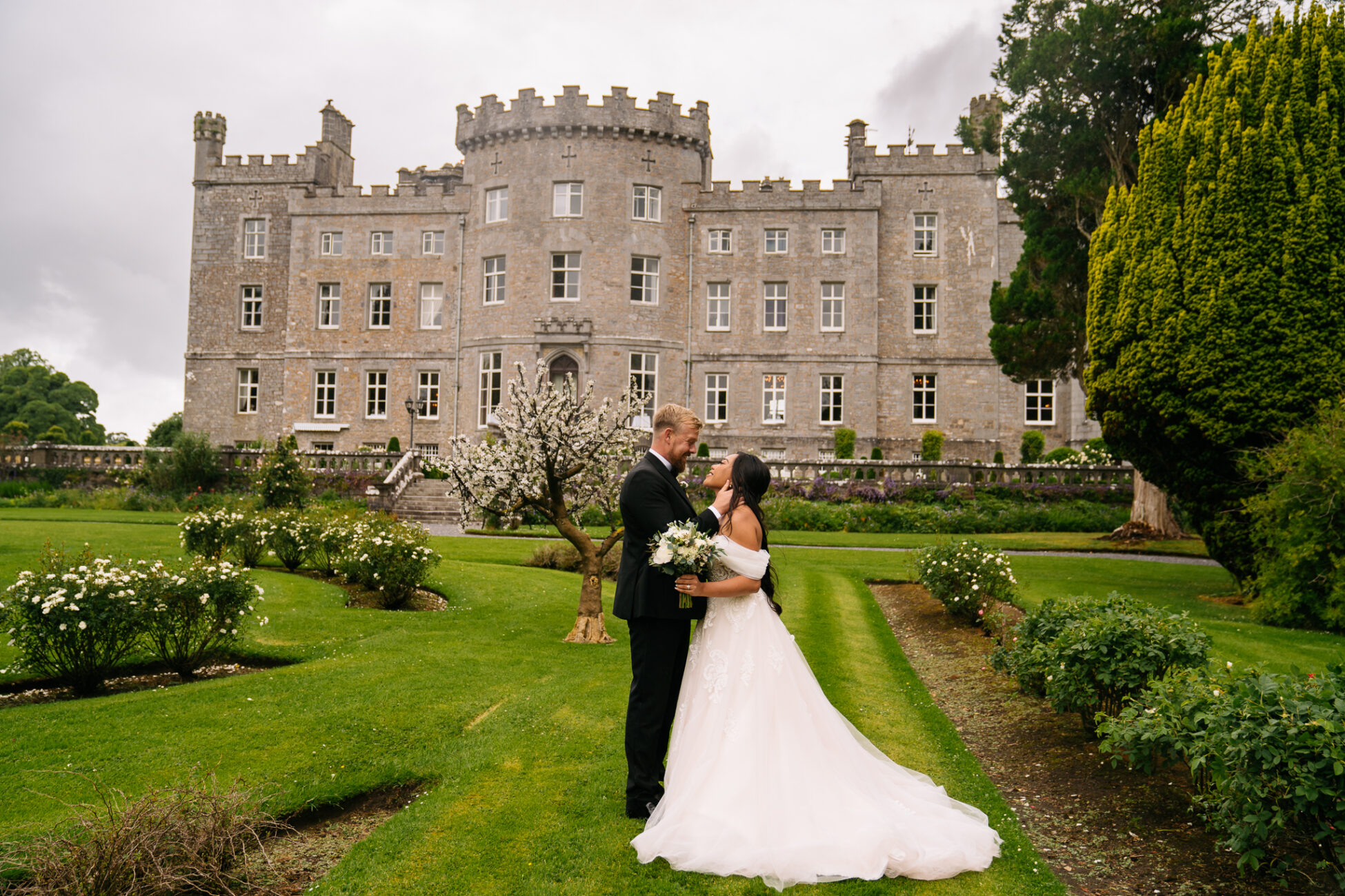 A man and woman in wedding attire kissing in front of a large building