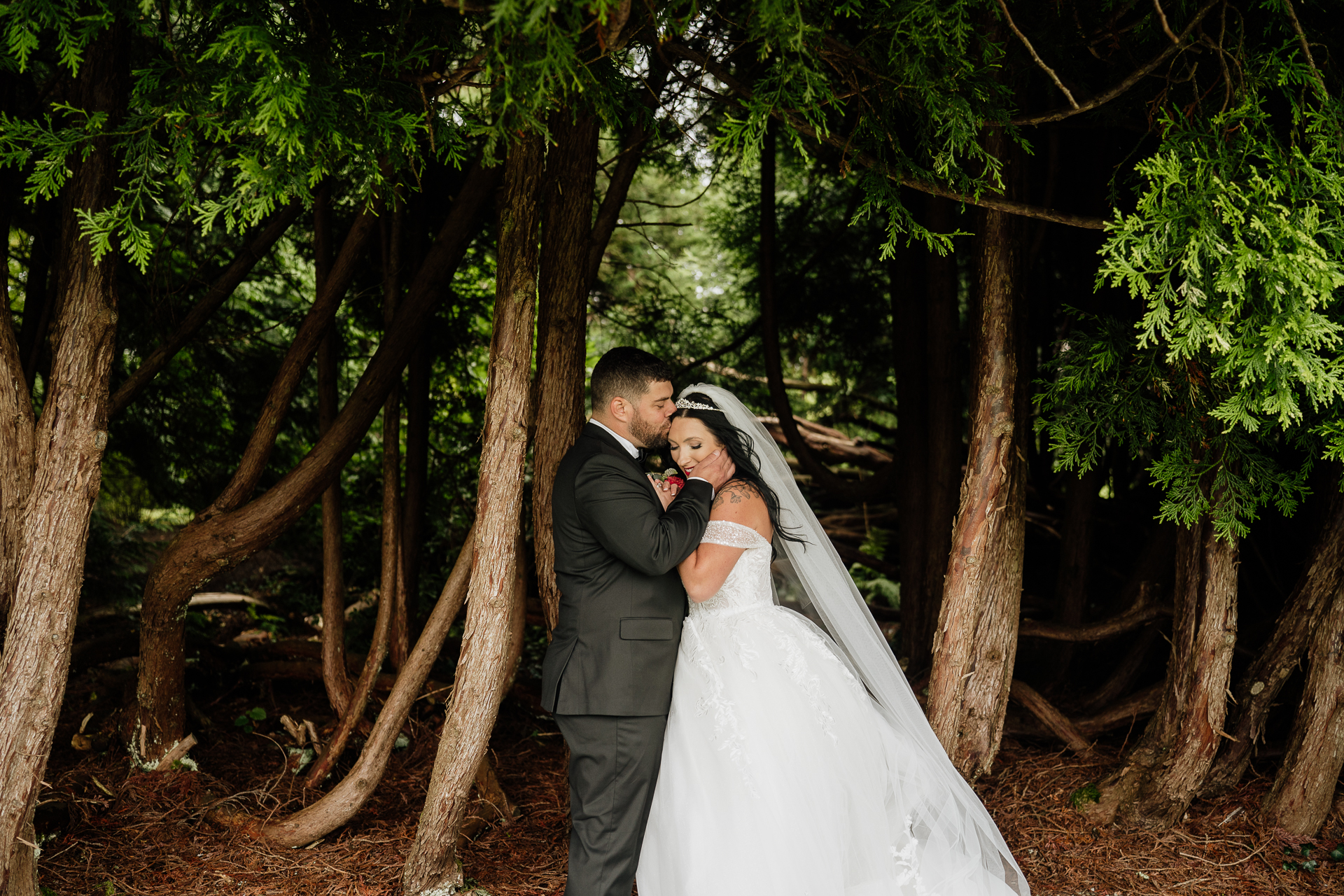 A man and woman kissing in a forest