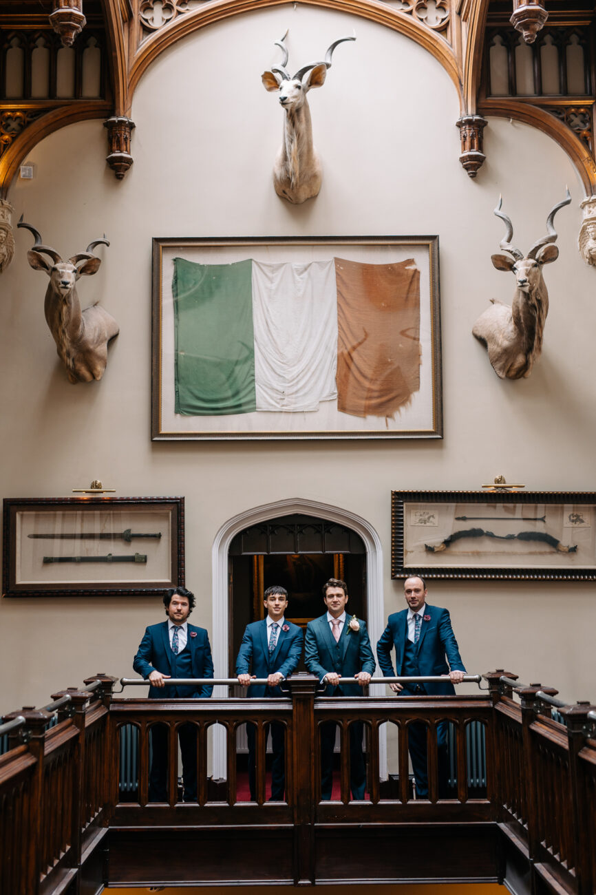 A group of men in blue robes sitting at a table in front of a wall with art on