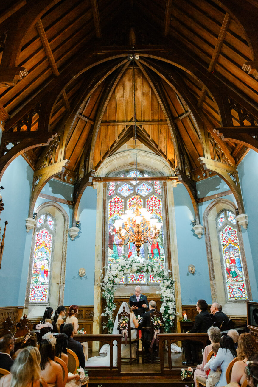 A church with a large stained glass window and a group of people sitting in pews