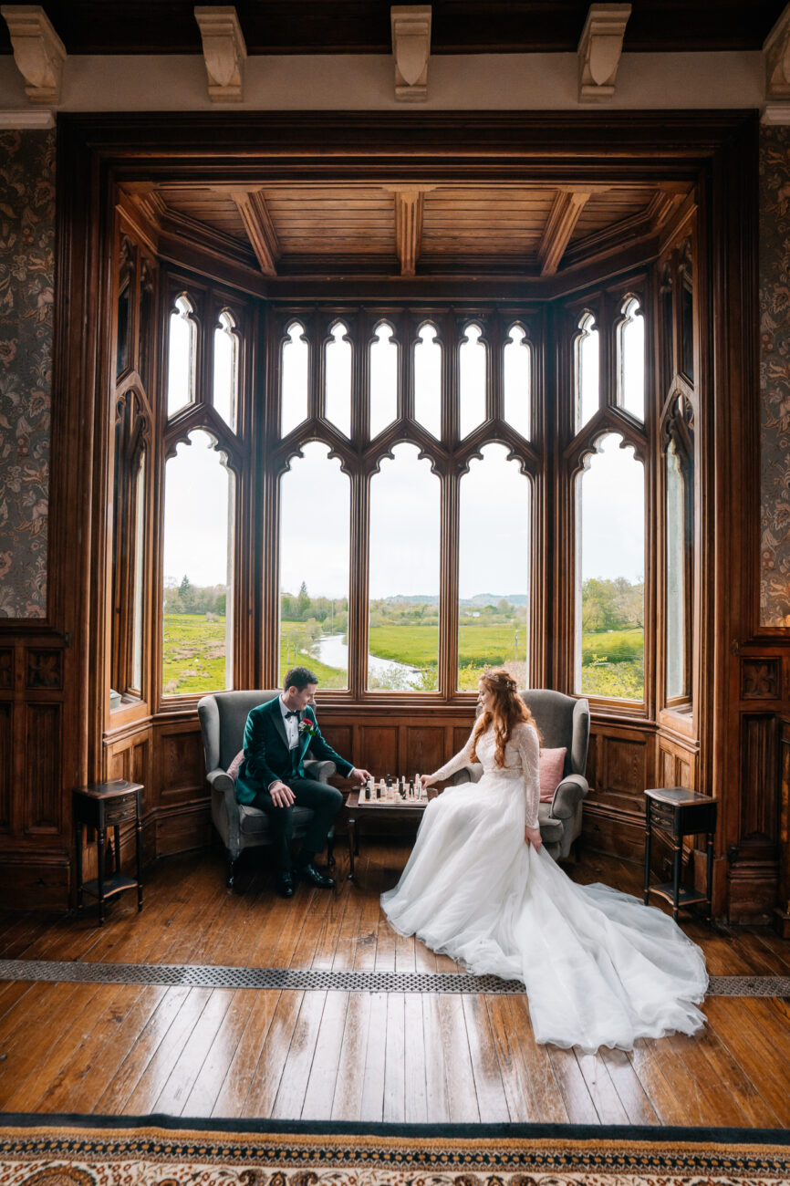 A bride and groom sitting in a room with large windows