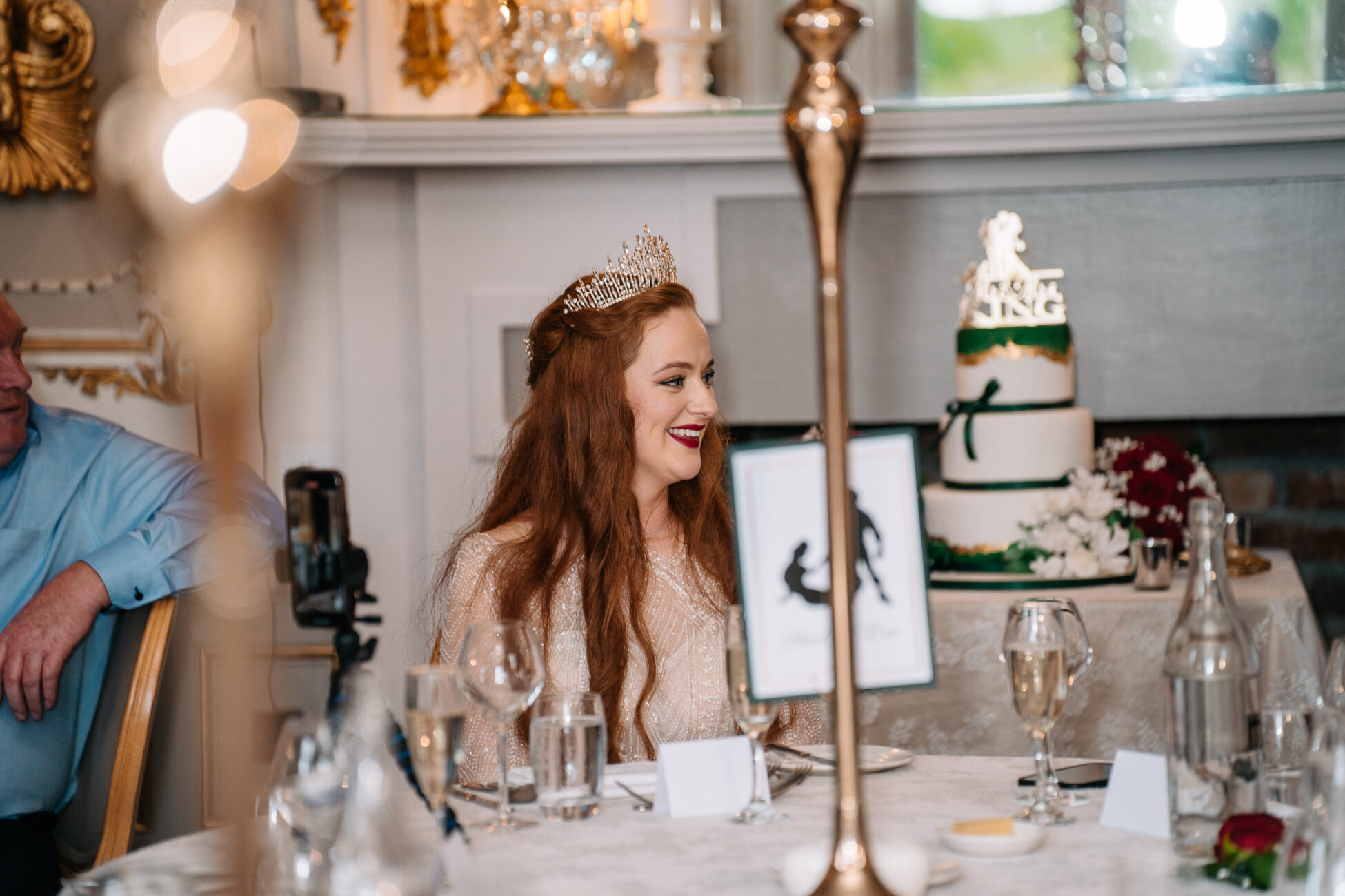 A person in a crown sitting at a table with a cake