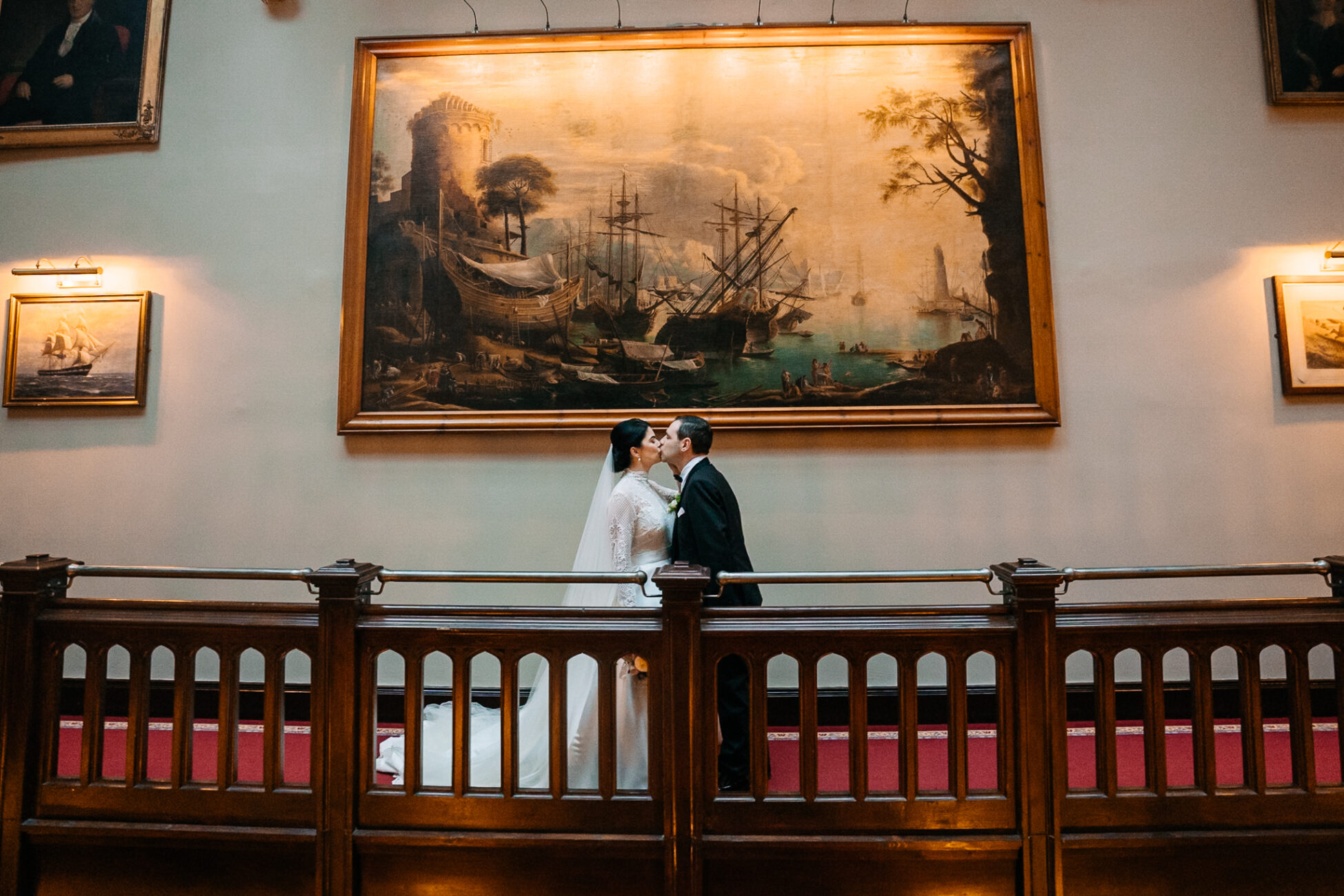 A man and woman kissing in front of a painting on a wall