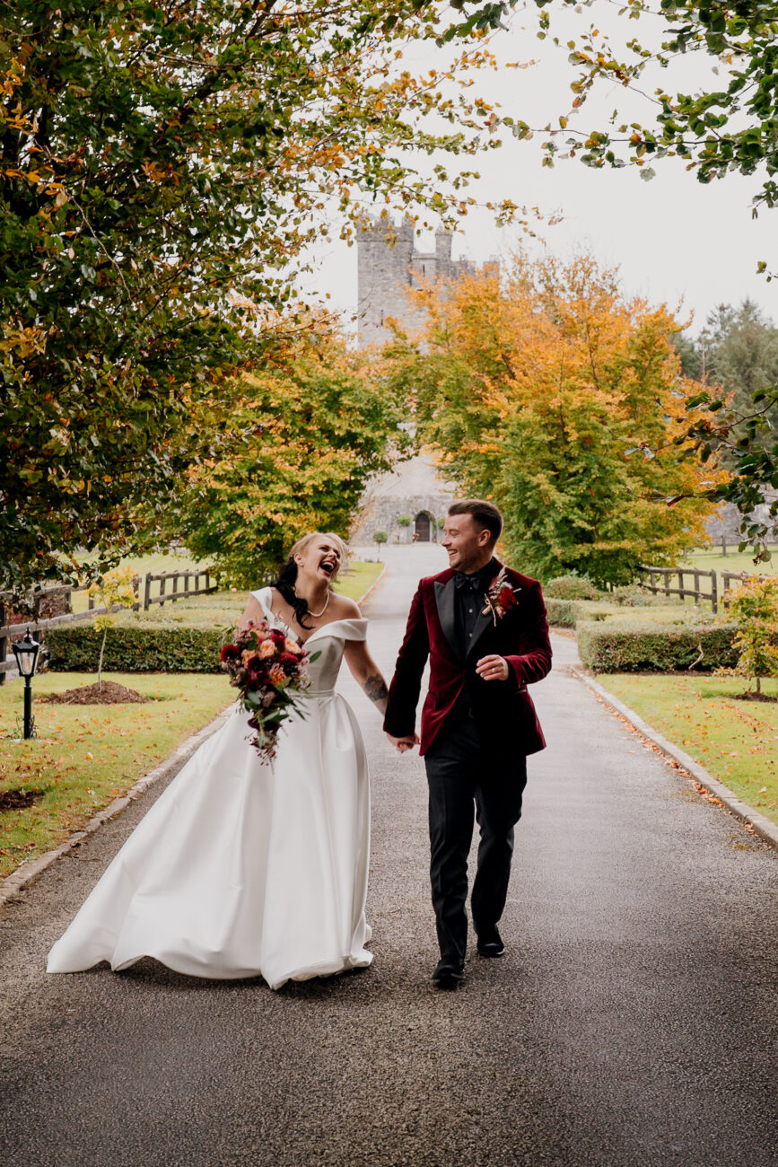 A man and woman walking down a road with trees on either side